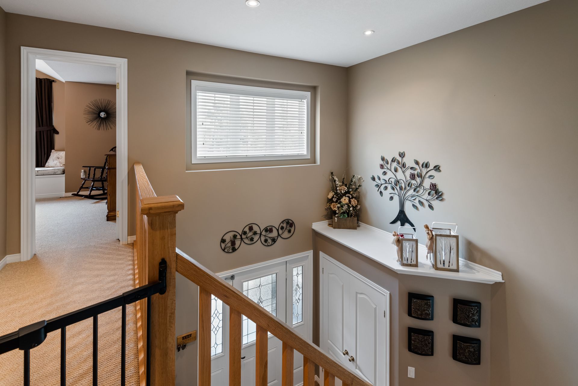 A staircase in a house with a wooden railing and a window.