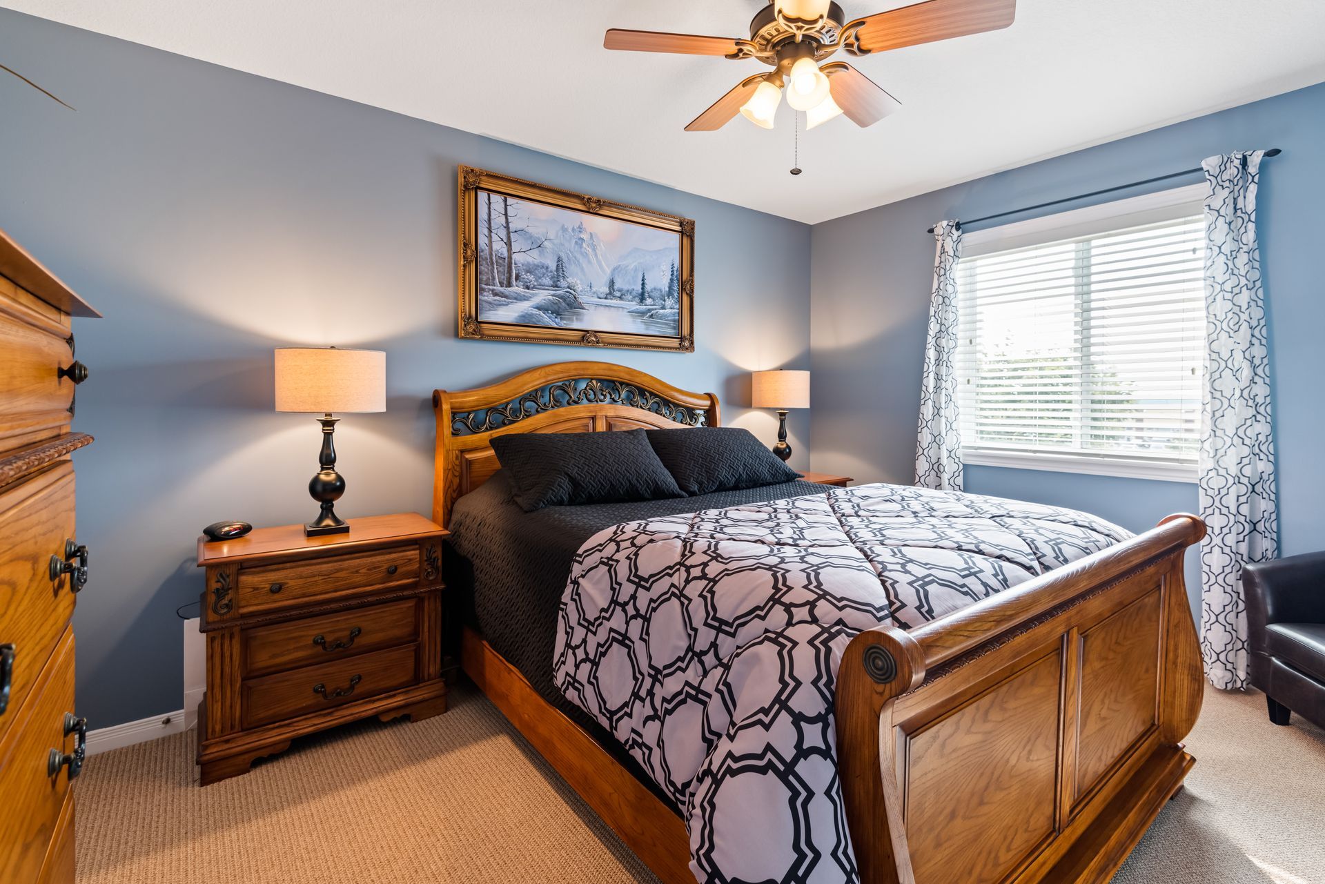 A bedroom with a king size bed , nightstand , dresser and ceiling fan.