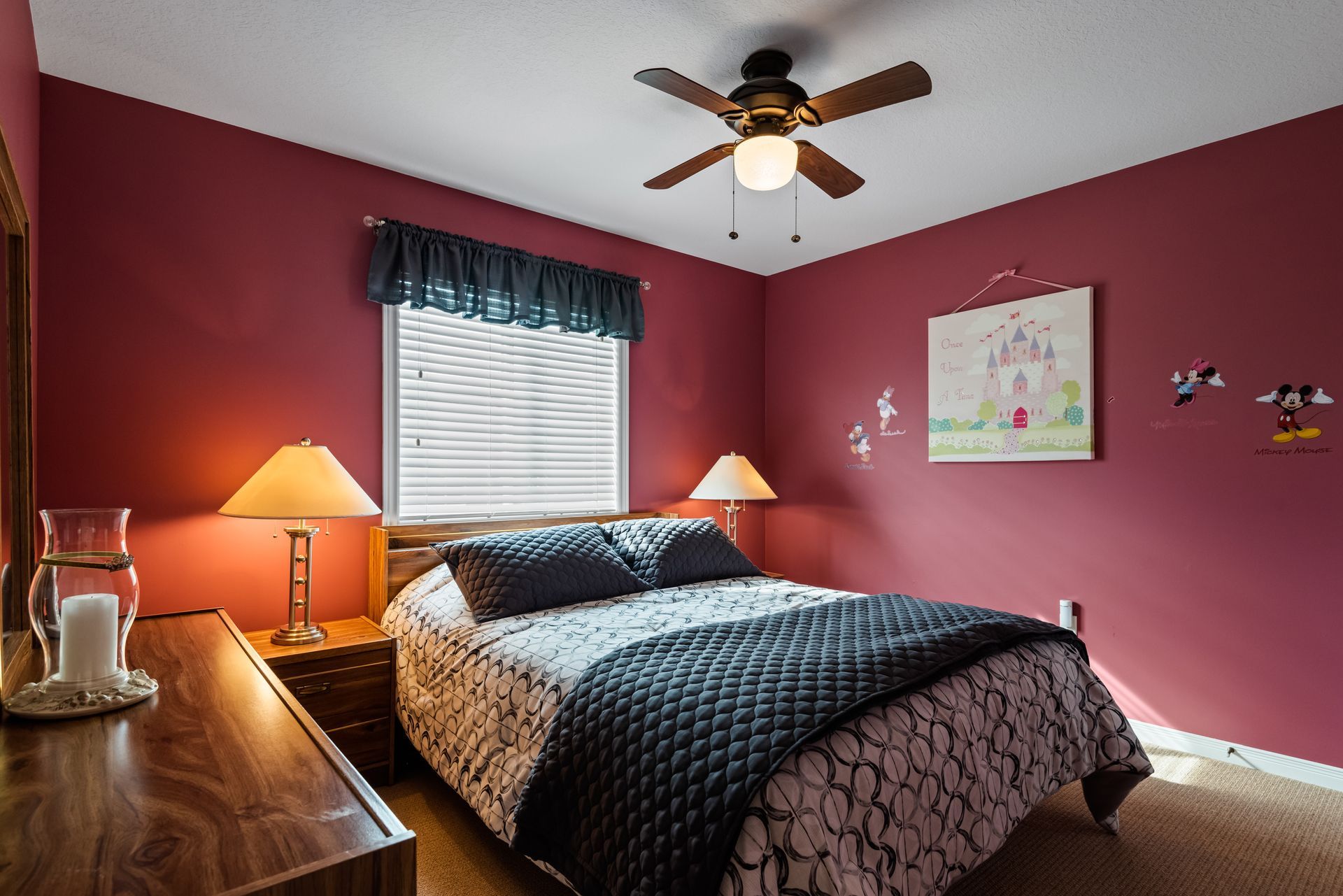 A bedroom with red walls and a ceiling fan