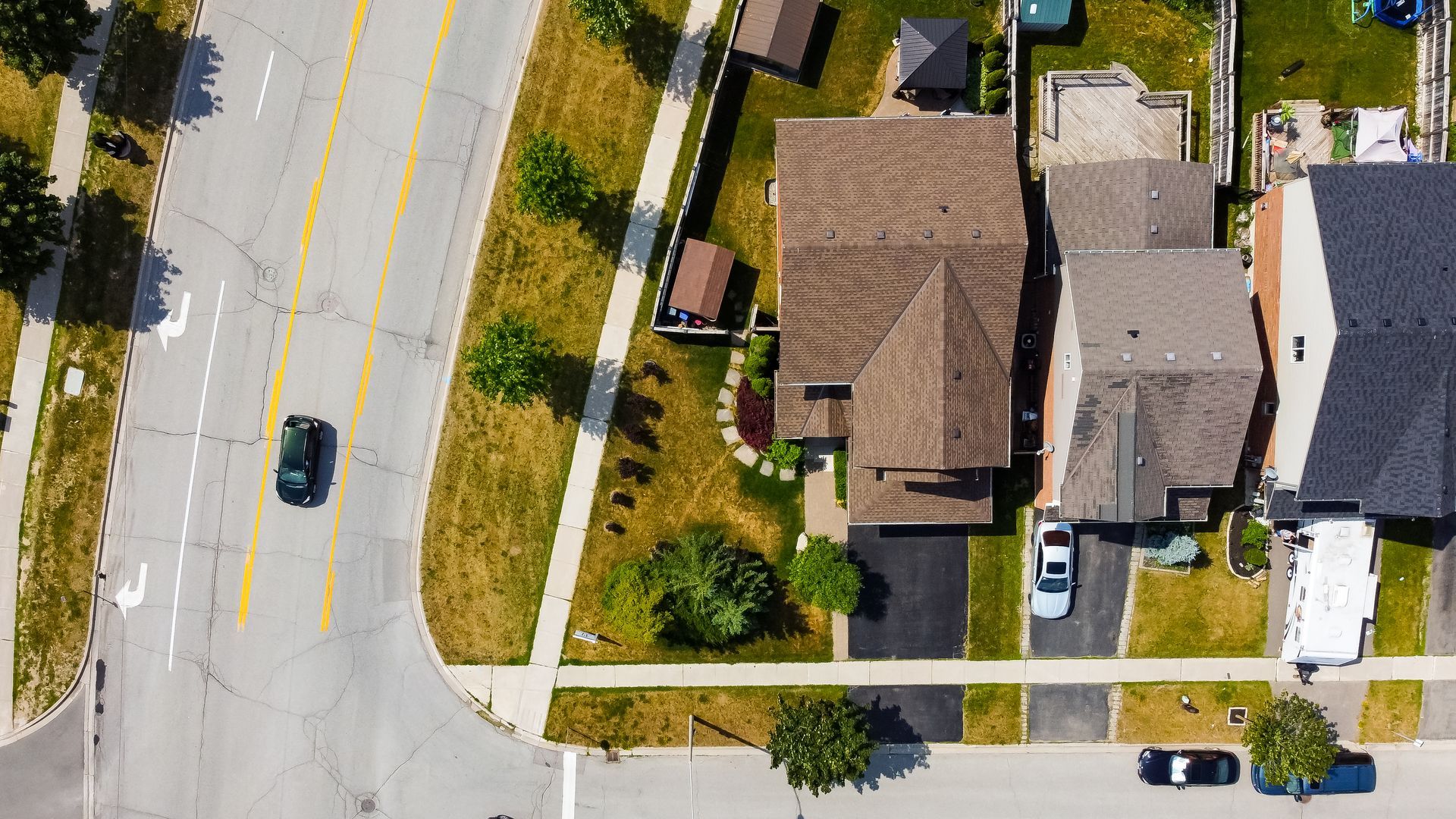 An aerial view of a residential neighborhood with a car driving down the street.