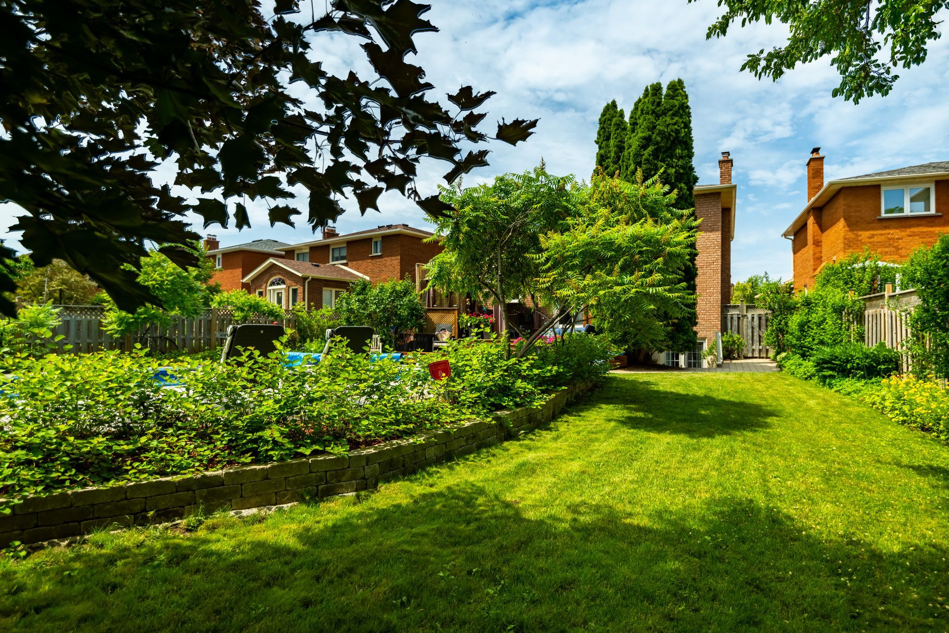 A lush green backyard with a brick house in the background