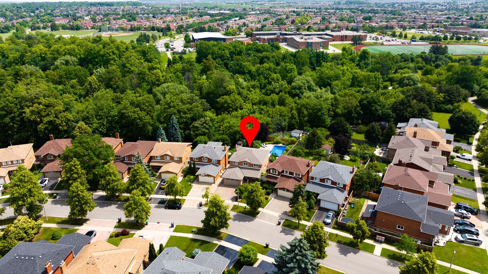 An aerial view of a residential area with a red marker pointing to a house.