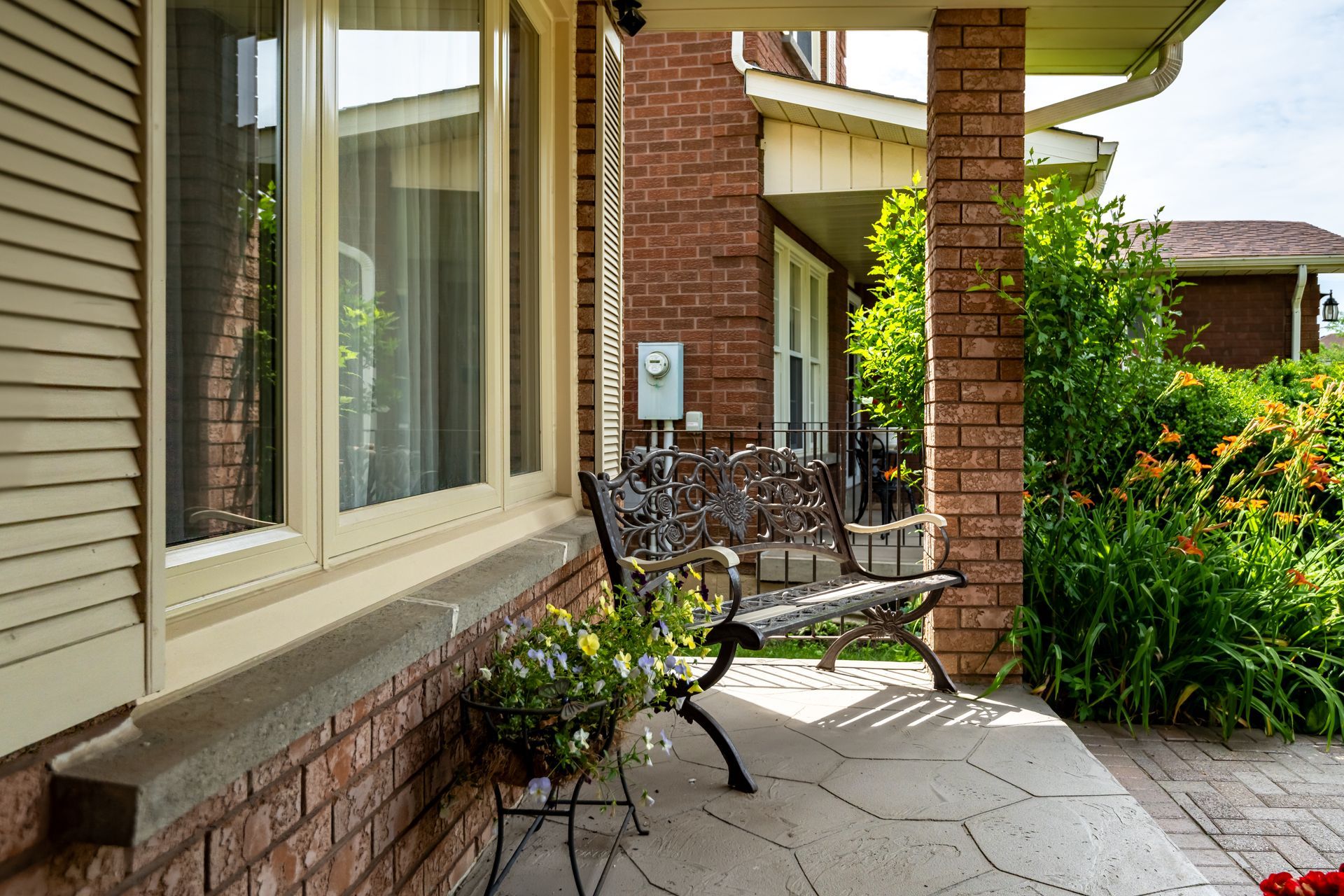 There is a bench on the porch of a brick house.