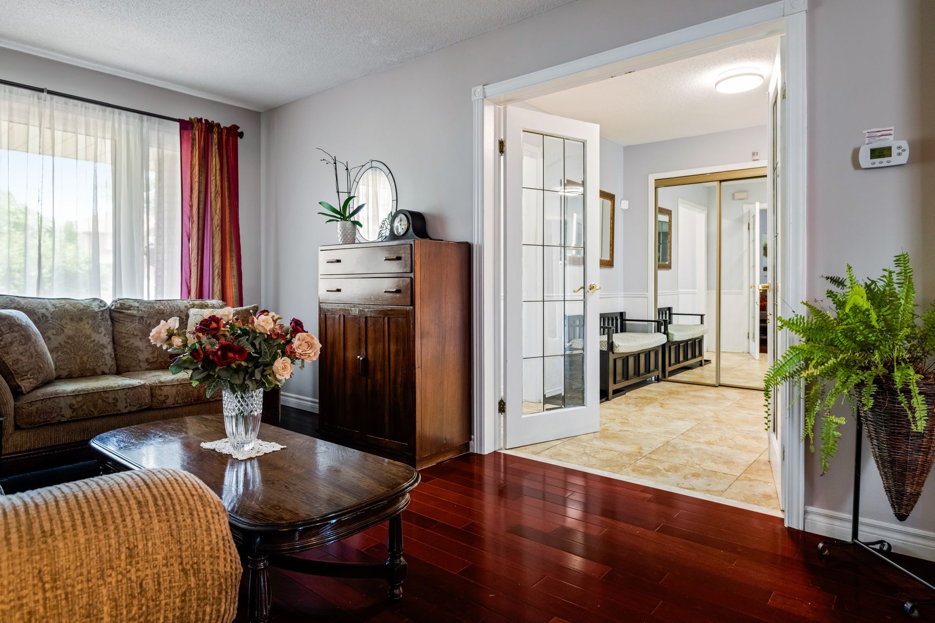 a living room with hardwood floors , a couch , a coffee table and a vase of flowers .