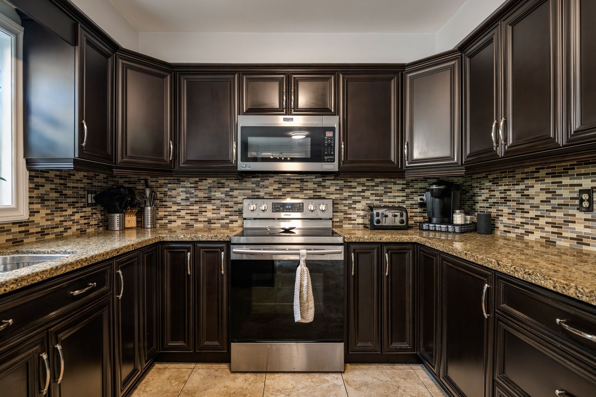 a kitchen with dark cabinets , stainless steel appliances and granite counter tops .