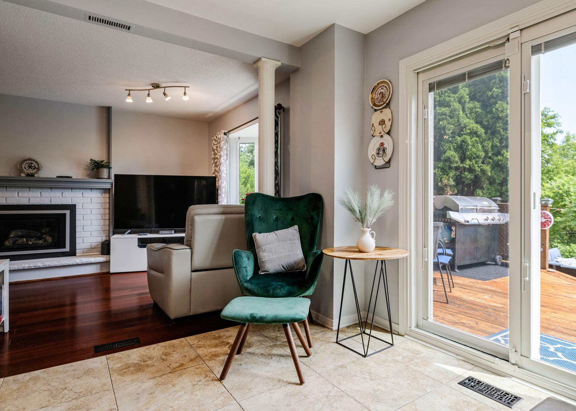 A living room with a green chair and ottoman and a sliding glass door.