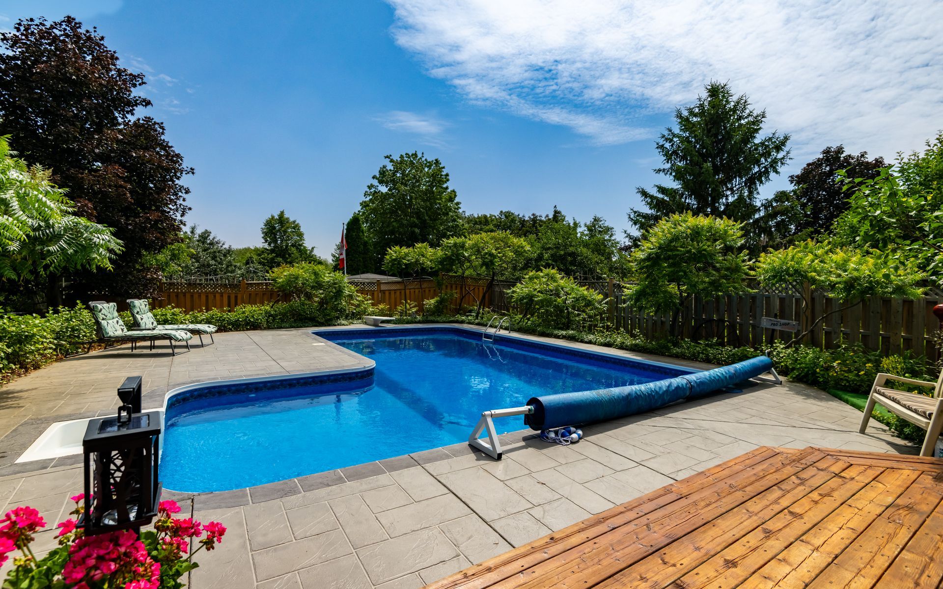 A large swimming pool is surrounded by trees and a wooden deck.