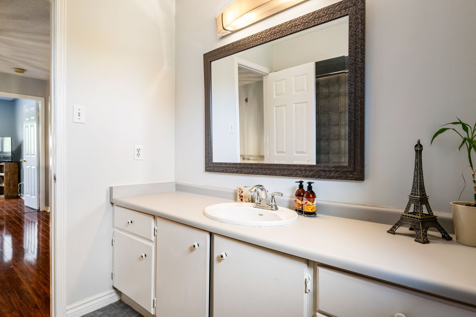 A bathroom with a sink , mirror and eiffel tower.
