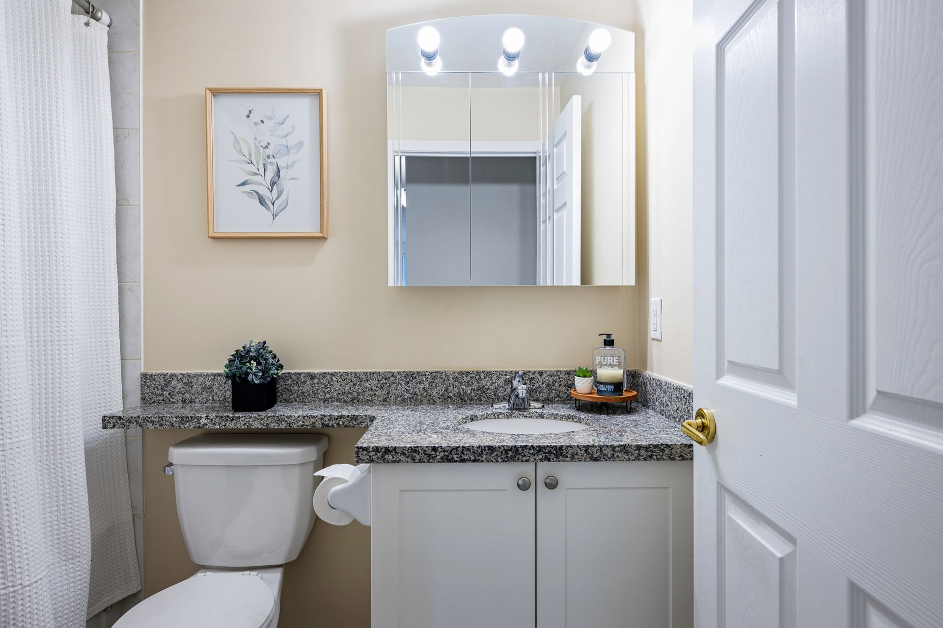 A bathroom with a toilet , sink and mirror.