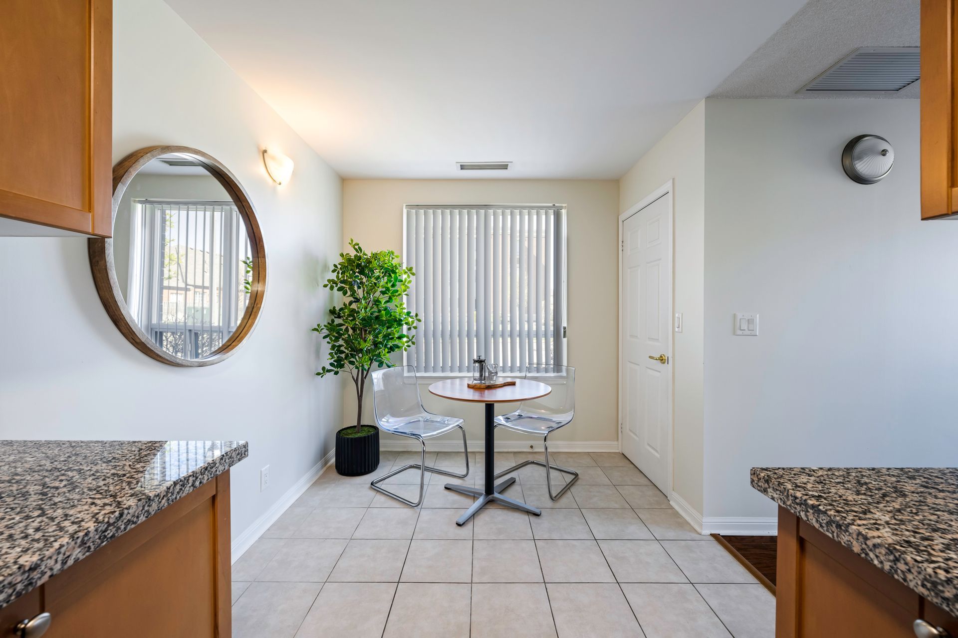 A dining room with a table and chairs and a mirror.