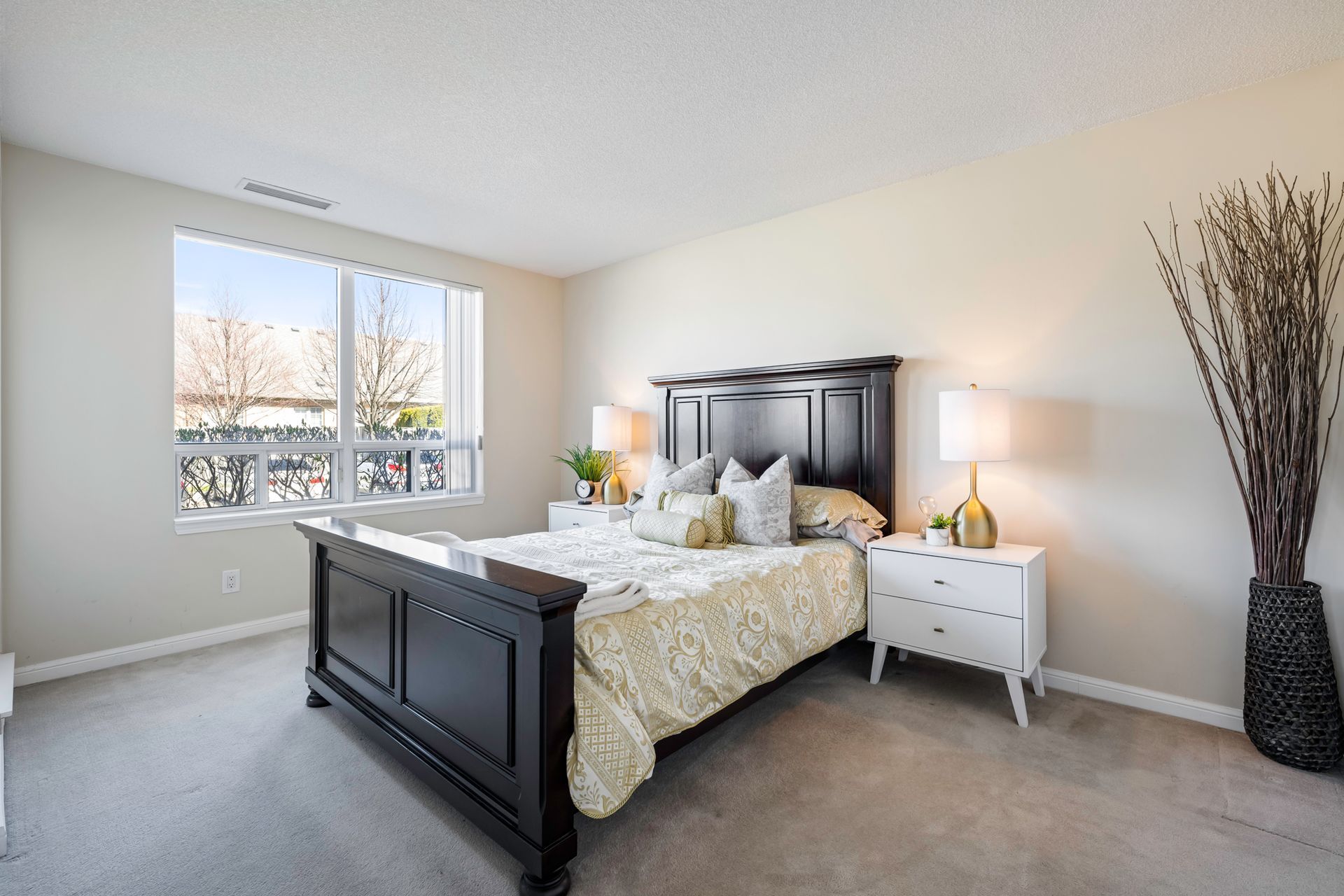 A bedroom with a large bed , nightstands , lamps and a window.