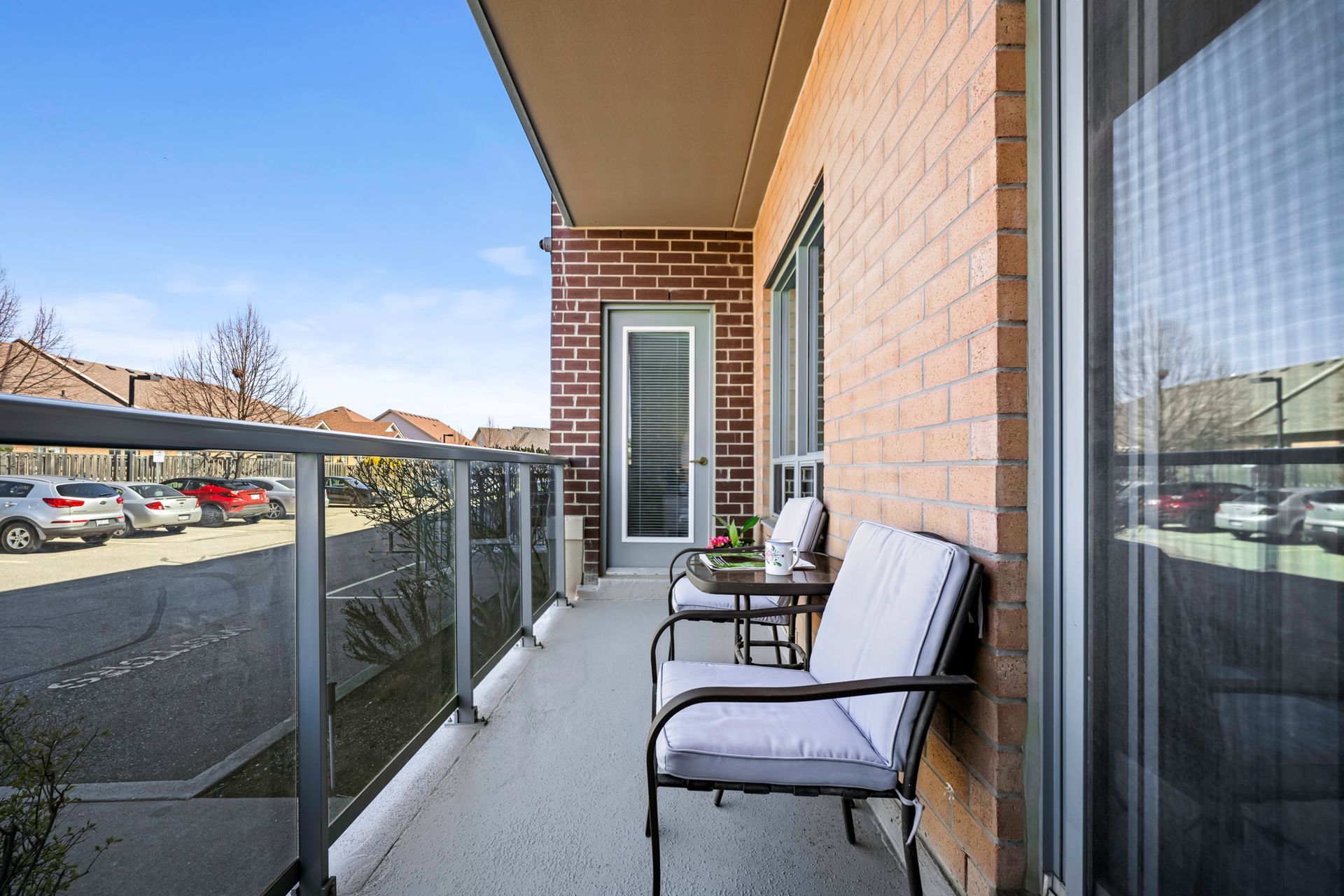 A balcony with two chairs and a table in front of a brick building.