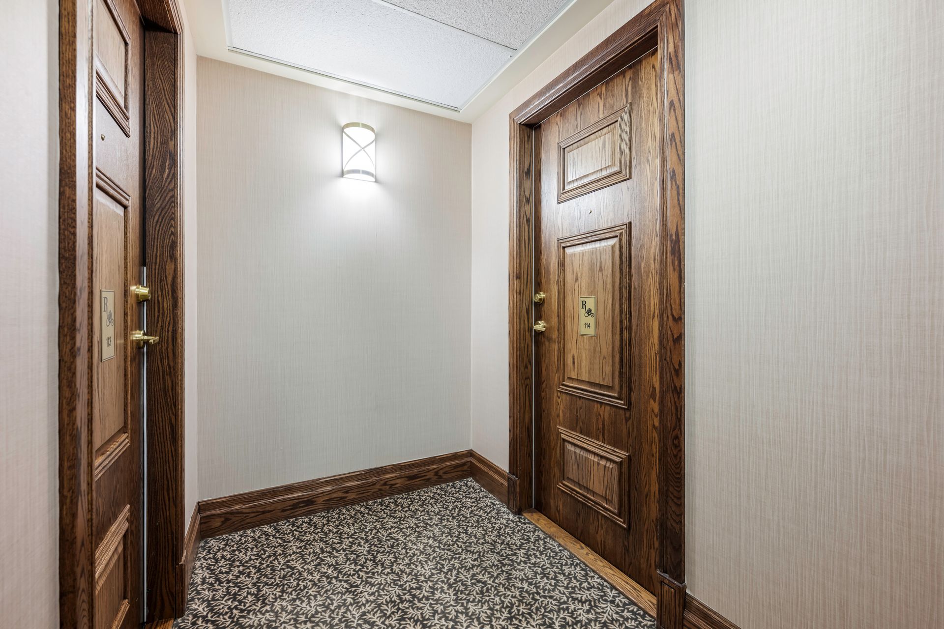 A hallway with two wooden doors and a carpeted floor.