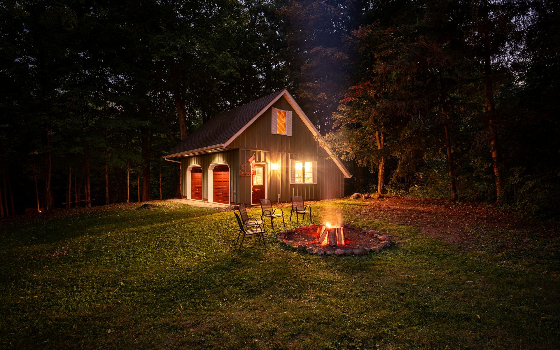 A small house with a fire pit in front of it at night.