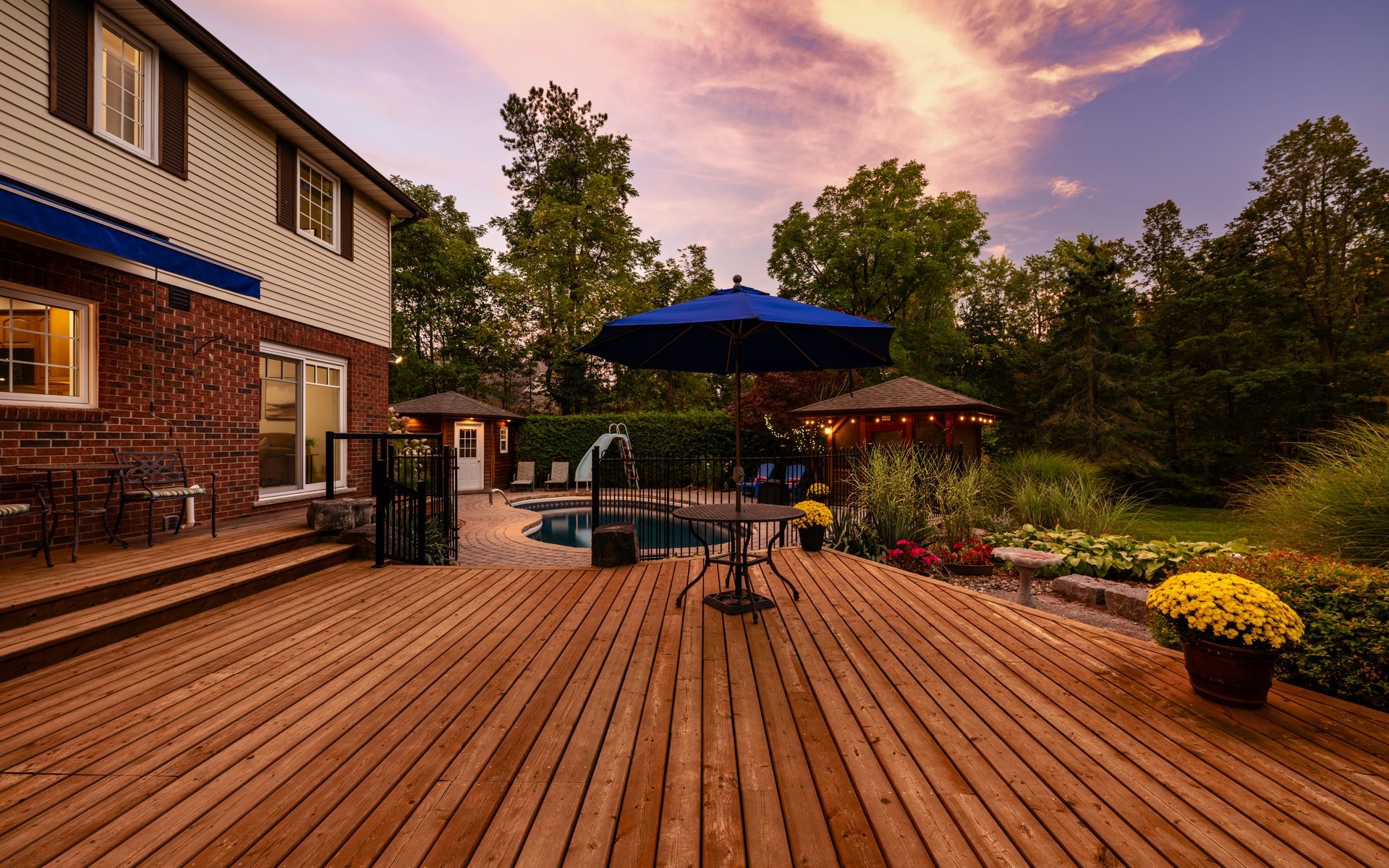 A large wooden deck with a table and umbrella in front of a house.