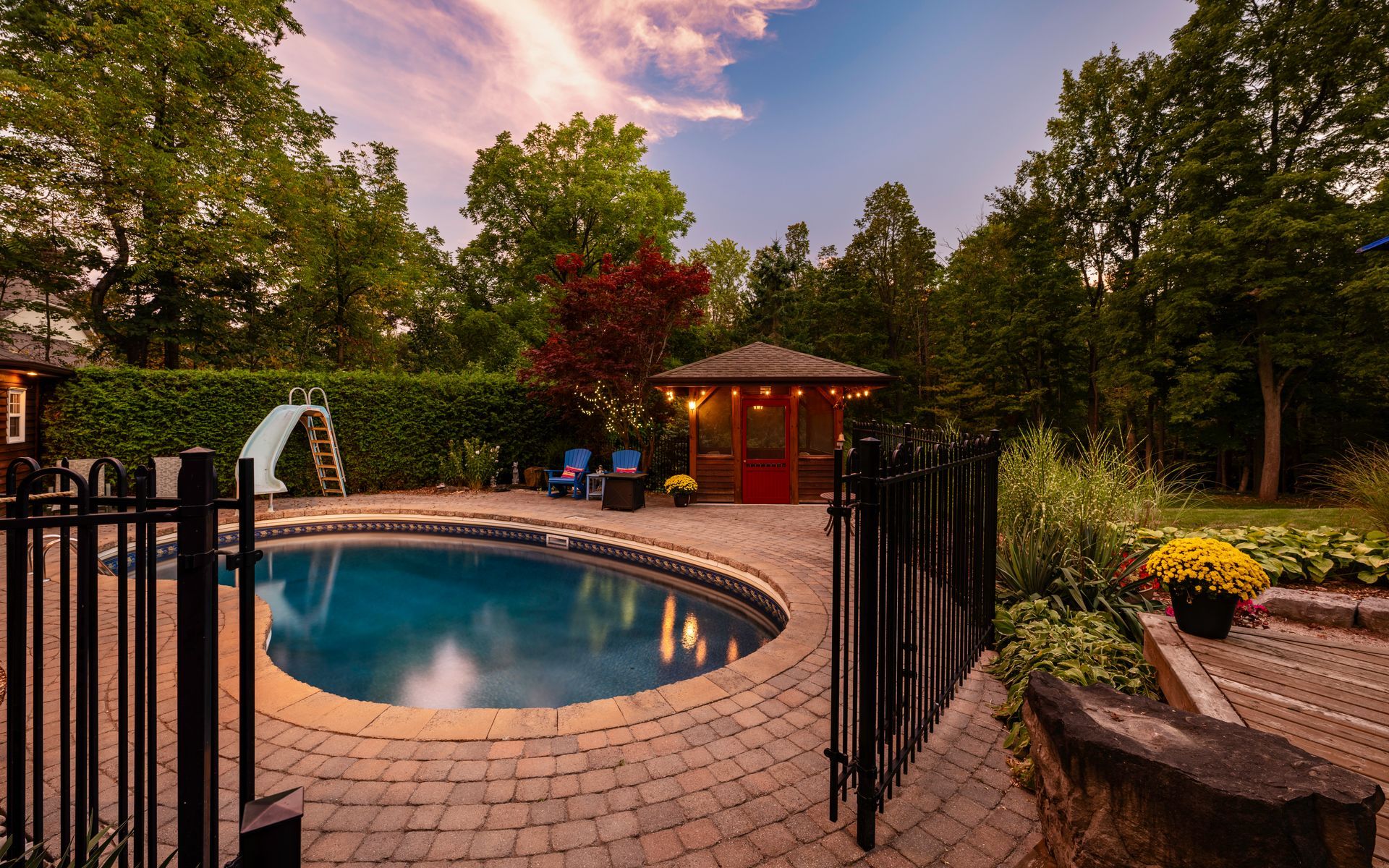 A large swimming pool is surrounded by a fence in a backyard.