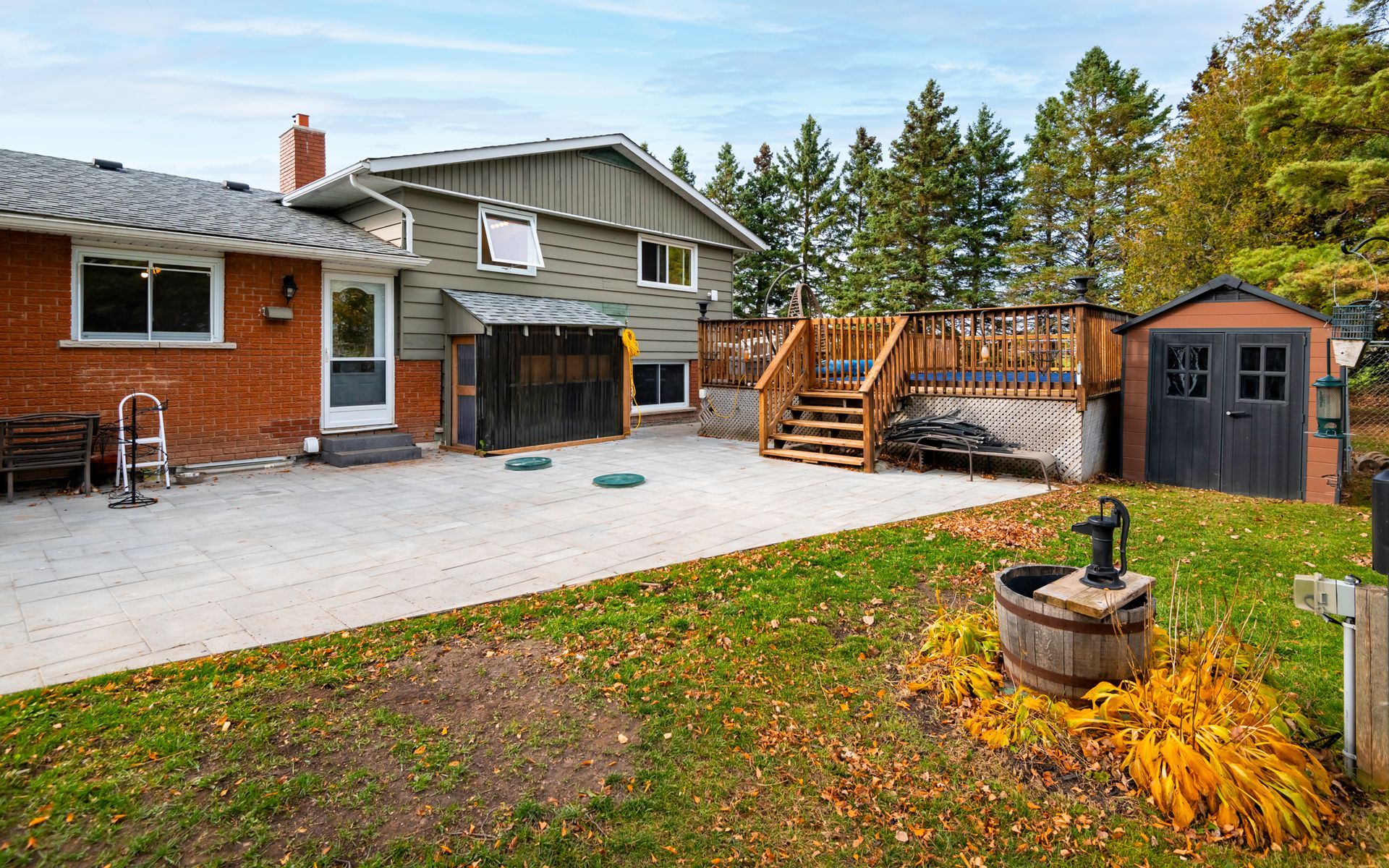 A large brick house with a large deck and a shed in the backyard.