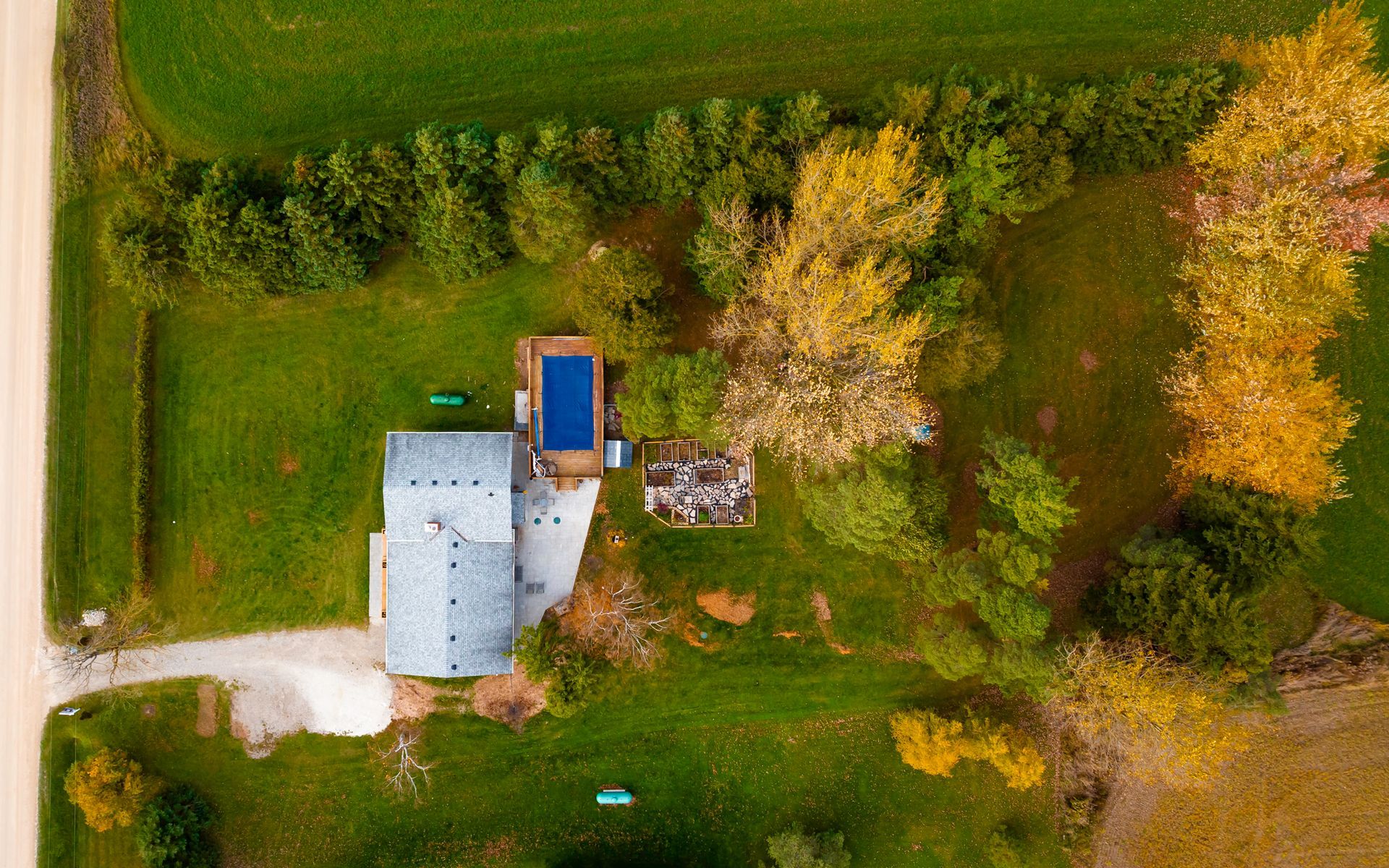 An aerial view of a house surrounded by trees and grass.
