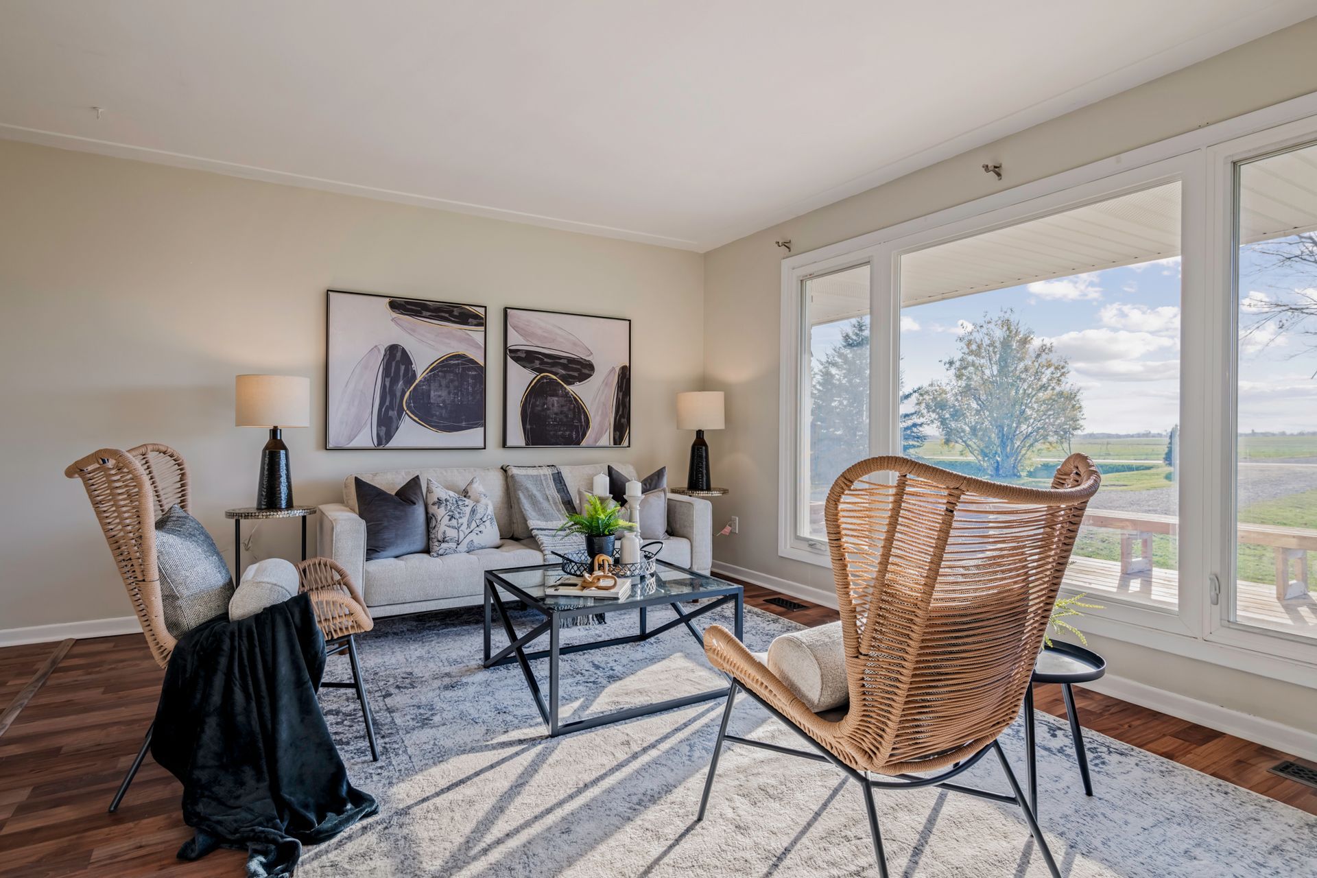 A living room with a couch , chairs , coffee table and large windows.