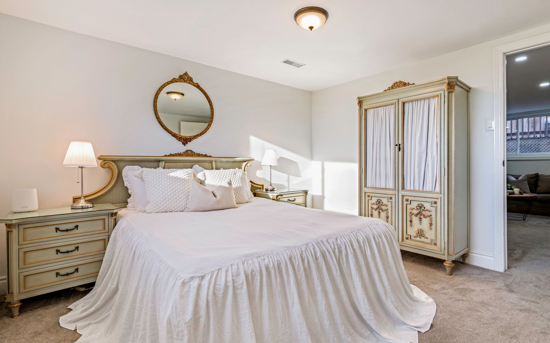 A bedroom with a bed , dresser , nightstand , mirror and wardrobe.