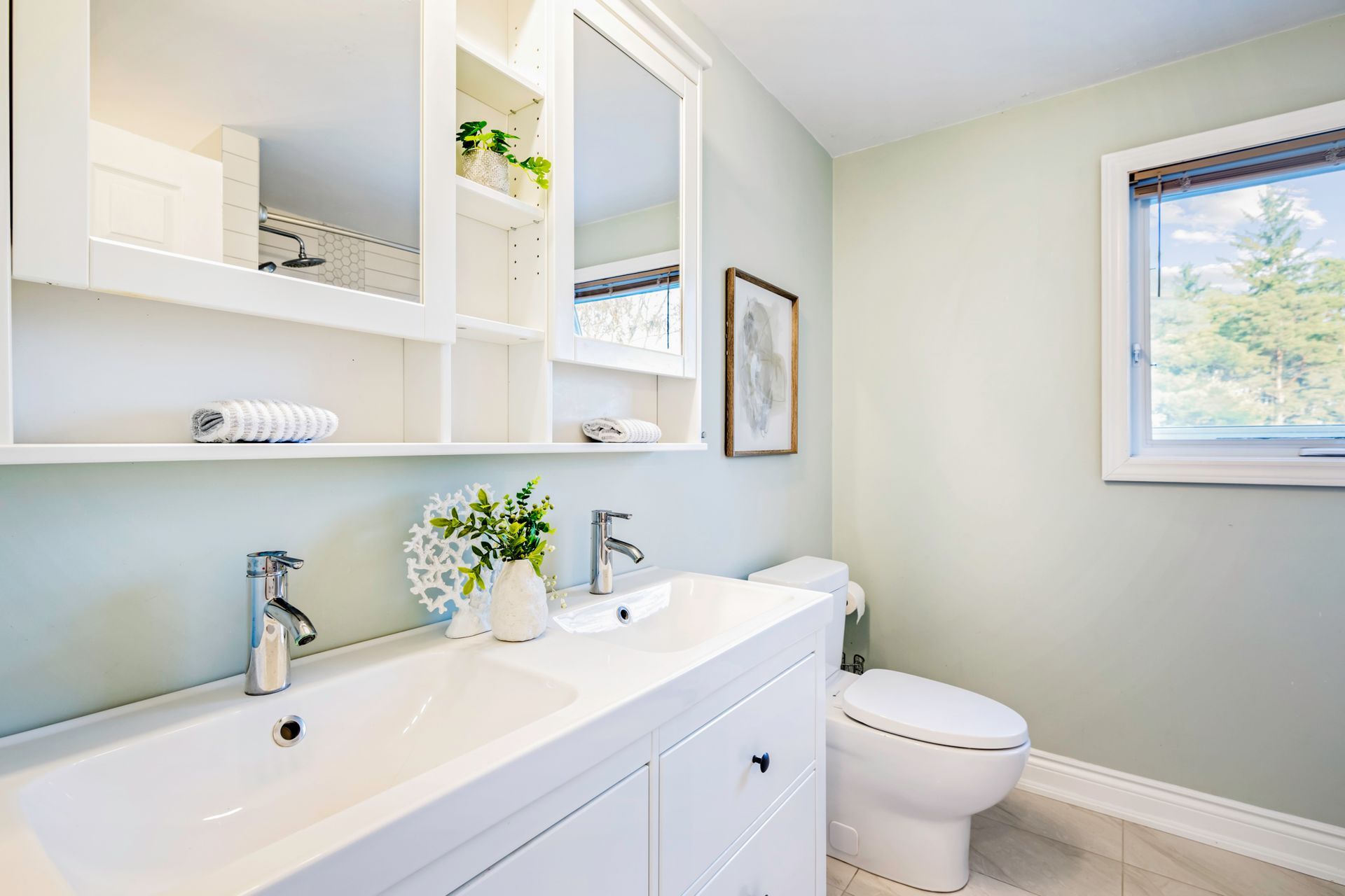 A bathroom with two sinks , a toilet , and a window.