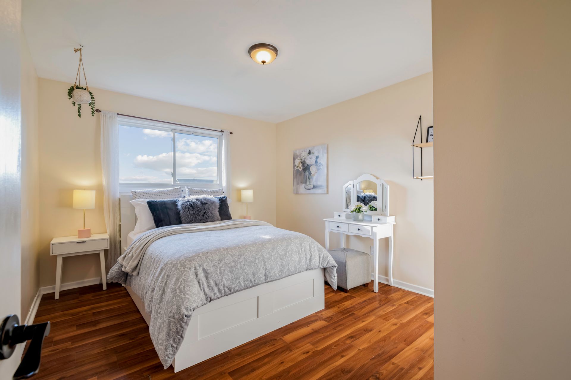 A bedroom with a bed , dresser , nightstand and window.