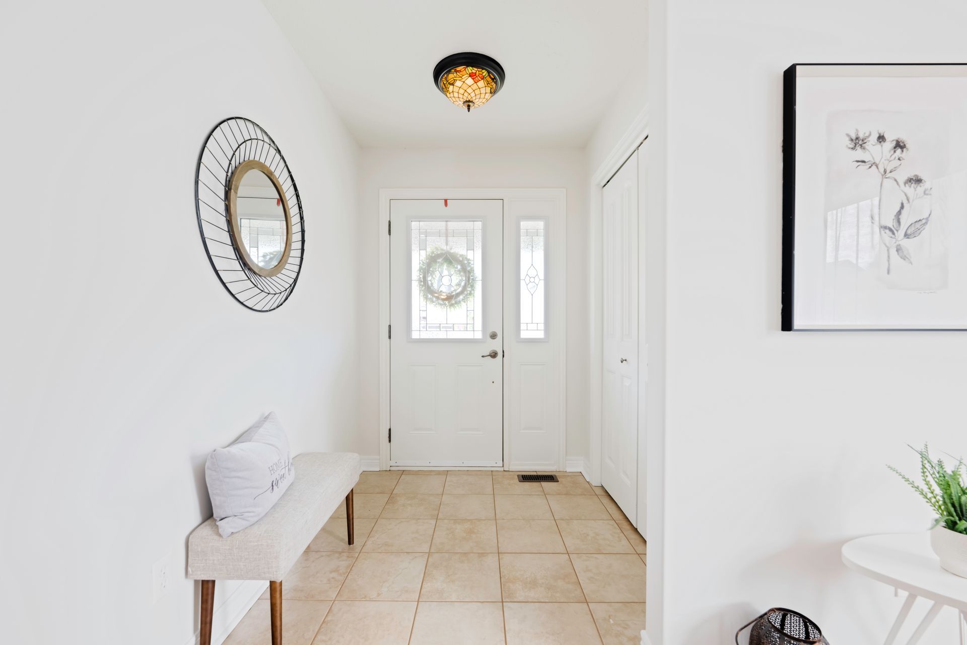 A hallway with a bench , mirror and picture on the wall.