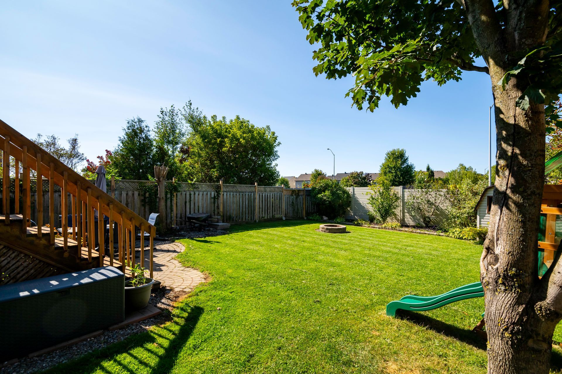 A backyard with a lush green lawn and a wooden deck.