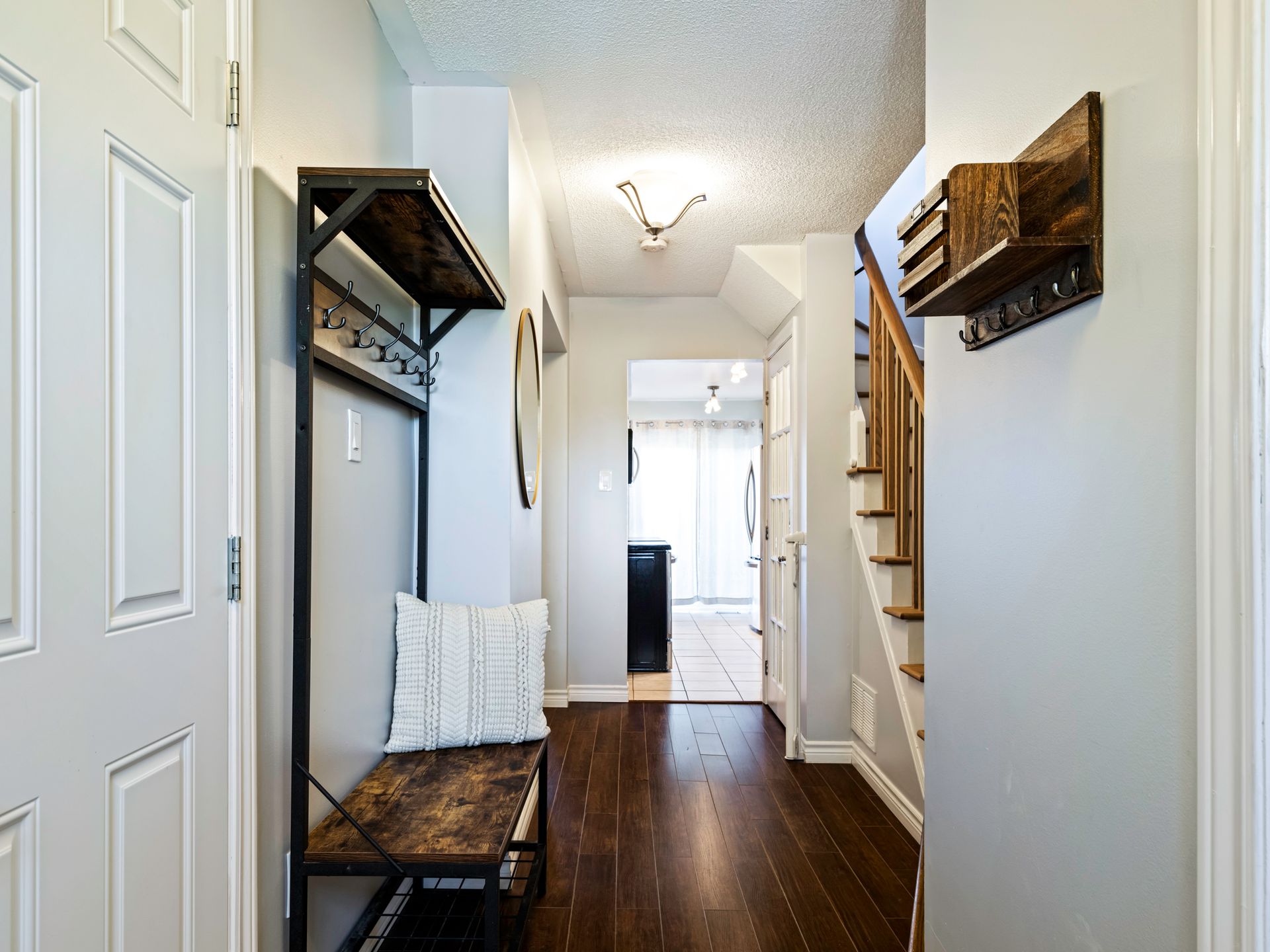 A hallway with a bench and stairs in a house.
