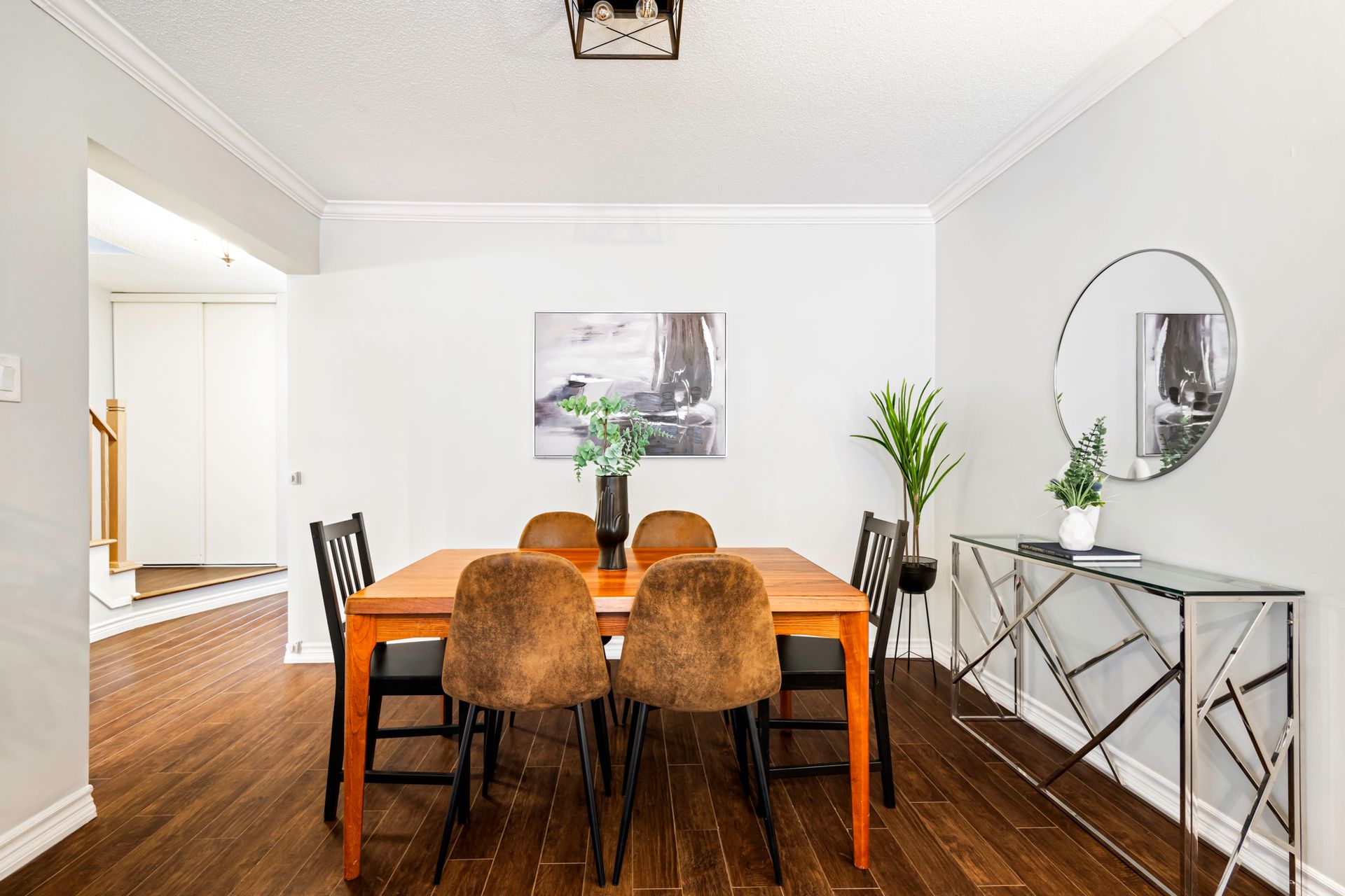A dining room with a table and chairs and a mirror.