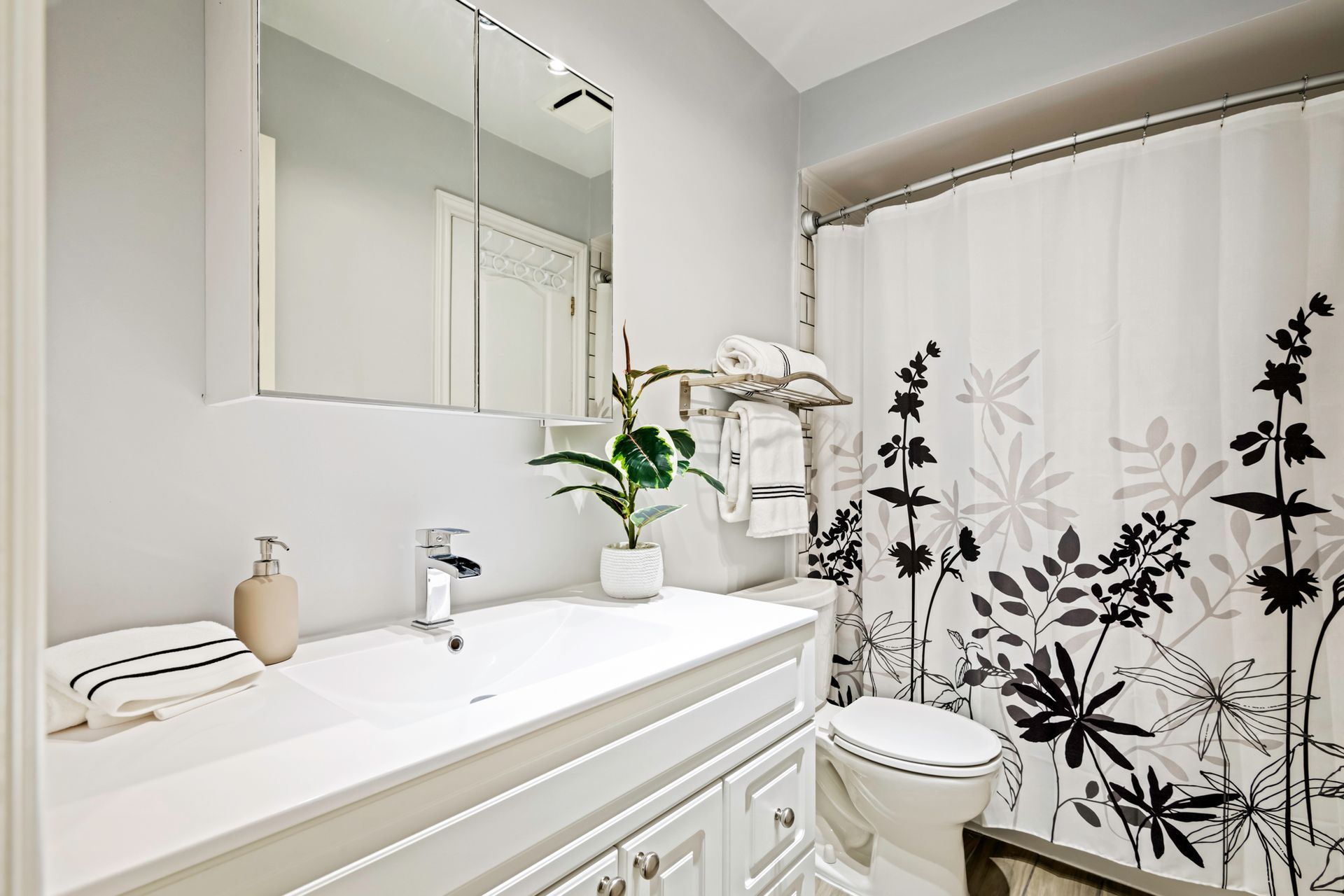 A bathroom with a sink , toilet , shower curtain and mirror.