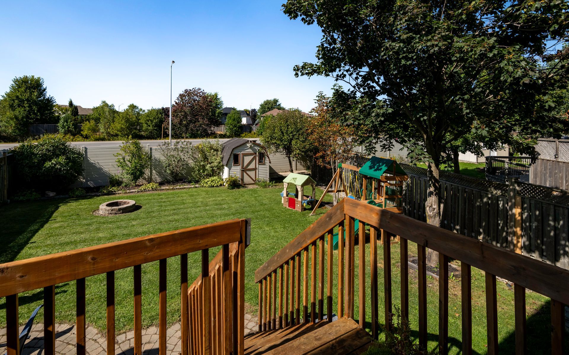 A backyard with a wooden deck and stairs leading up to it.
