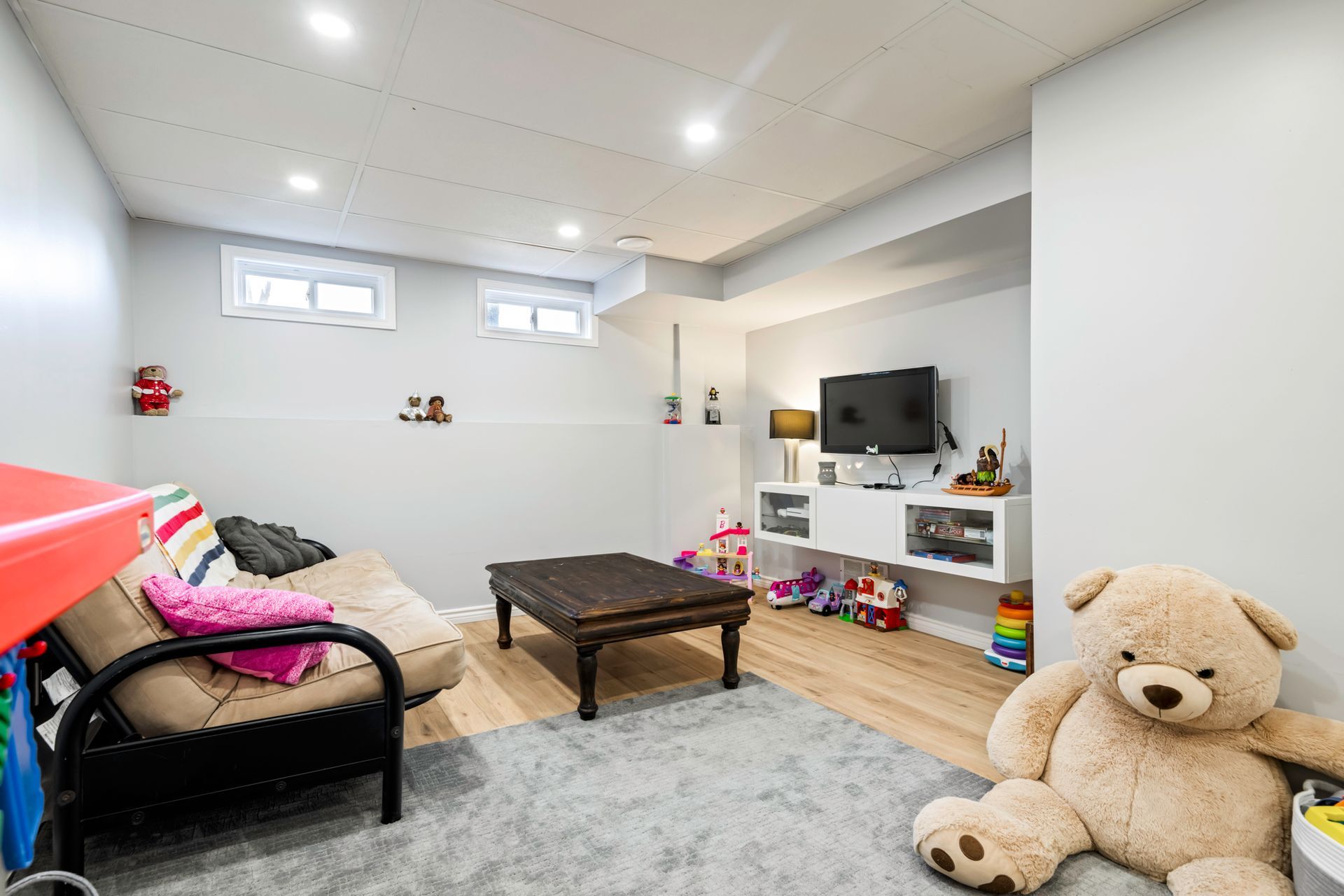 A living room with a couch , coffee table , teddy bear and television.