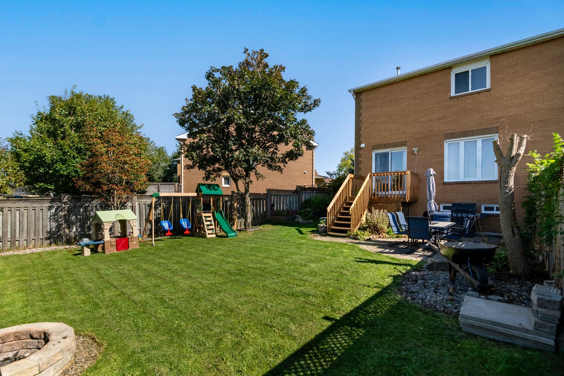 The backyard of a house with a playground and a fire pit.