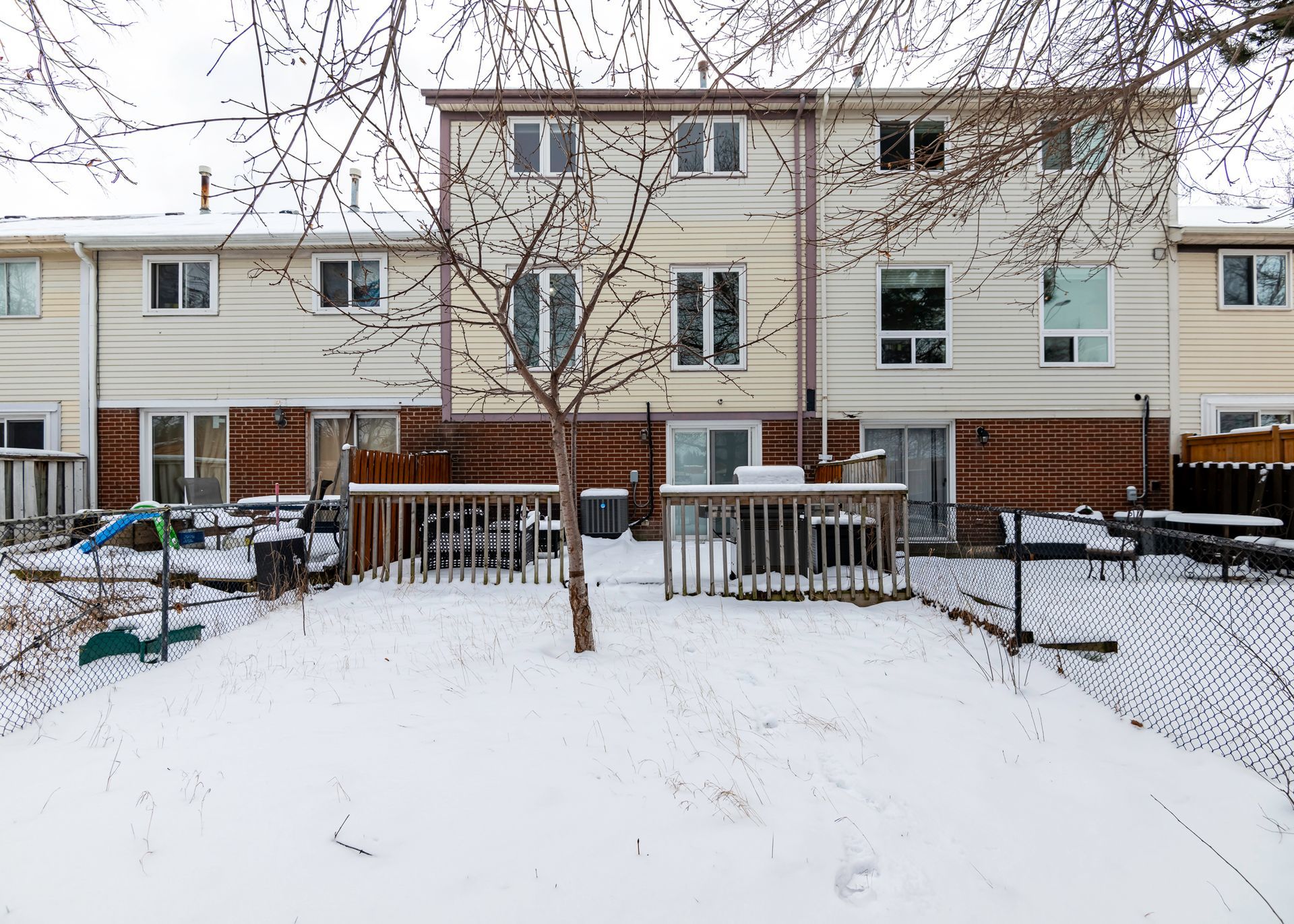 The backyard of a row of houses is covered in snow.