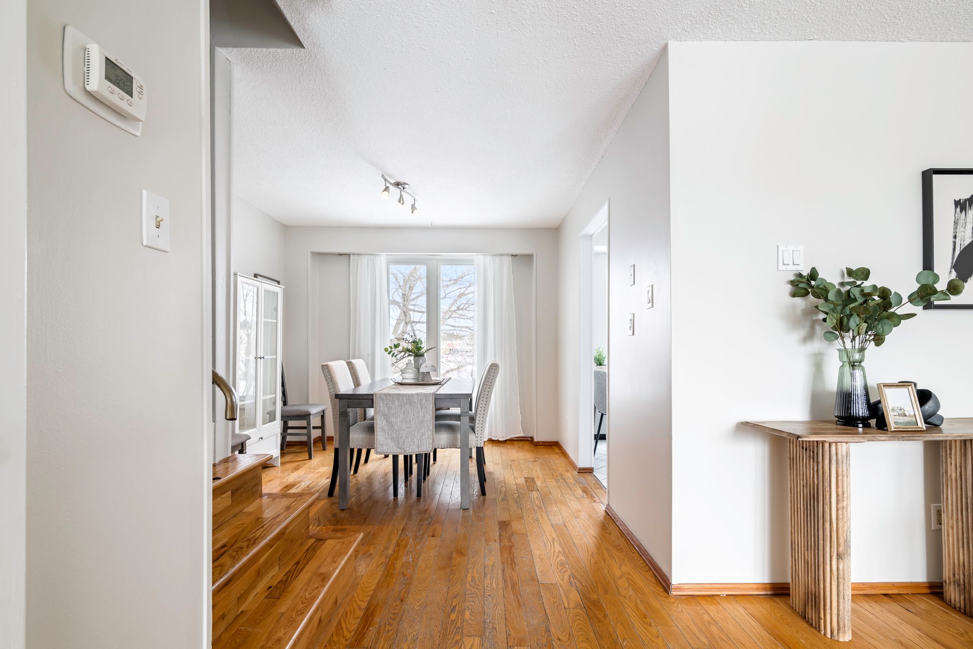 A hallway leading to a dining room with a table and chairs.