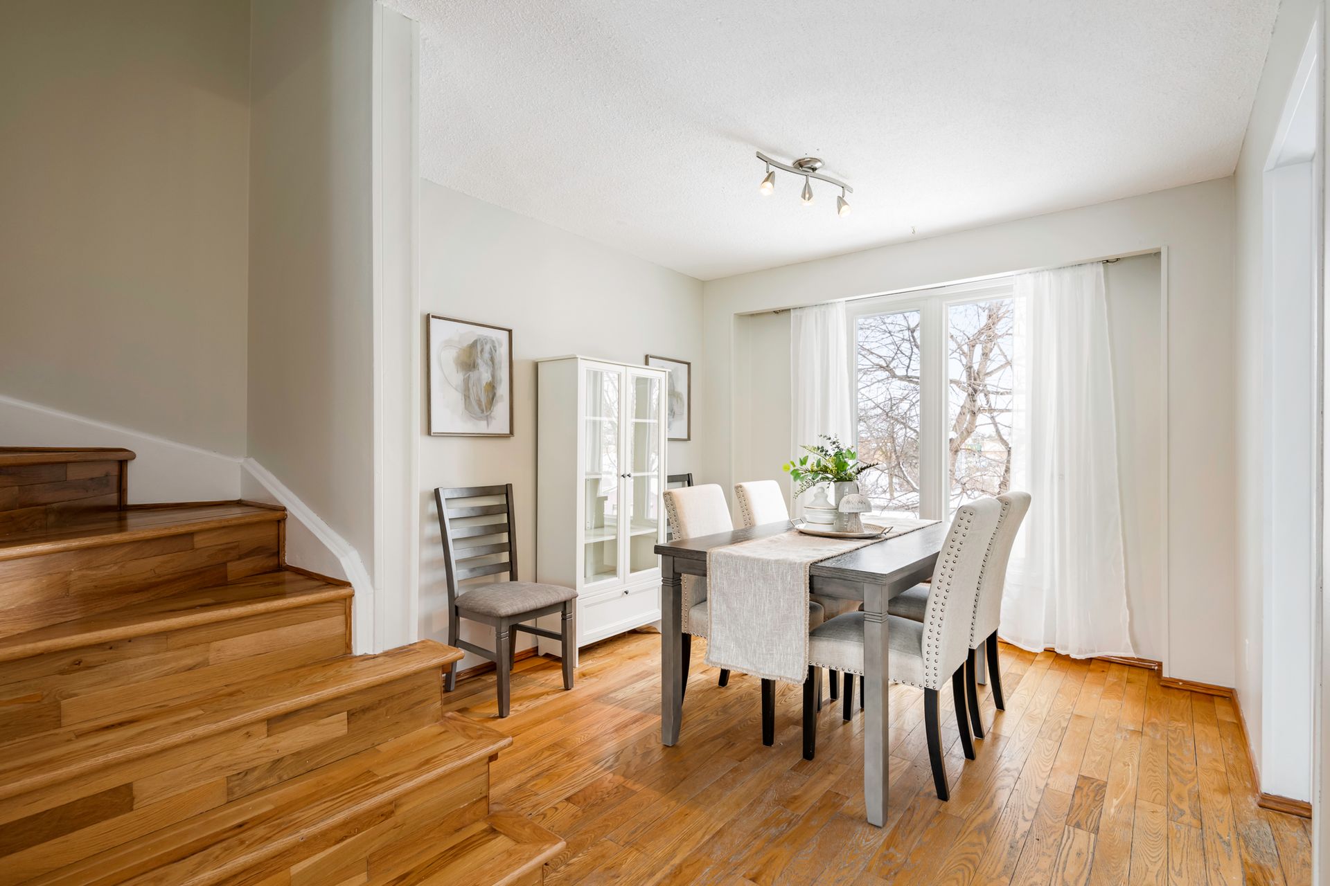 A dining room with a table and chairs and stairs.