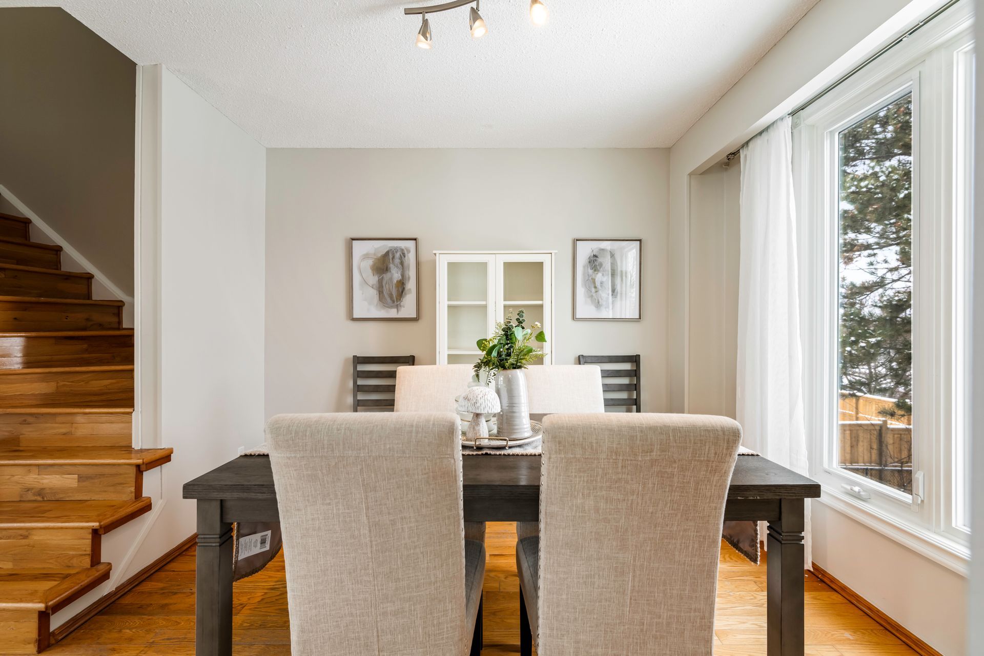 A dining room with a table and chairs and stairs.