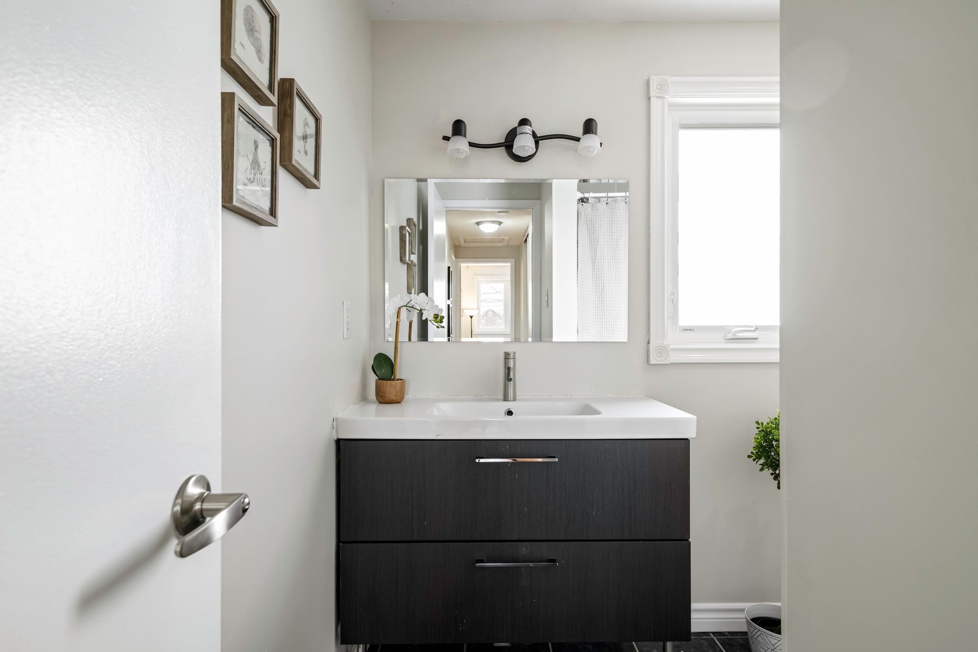 A bathroom with a sink , mirror and window.