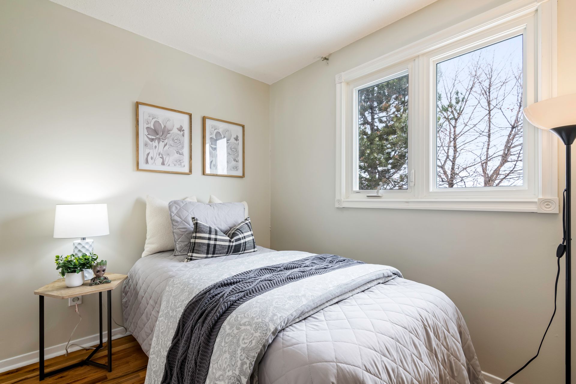 A bedroom with a bed , lamp , table and window.