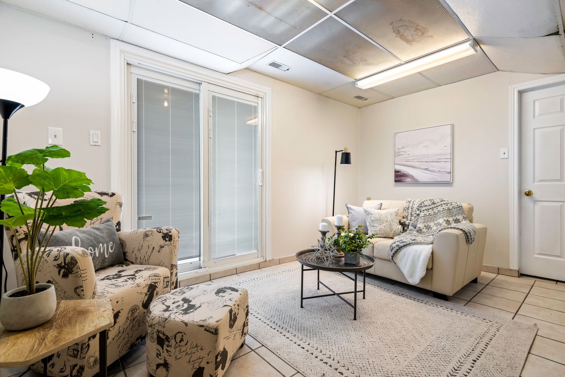 A living room with a couch , chair , coffee table and sliding glass doors.