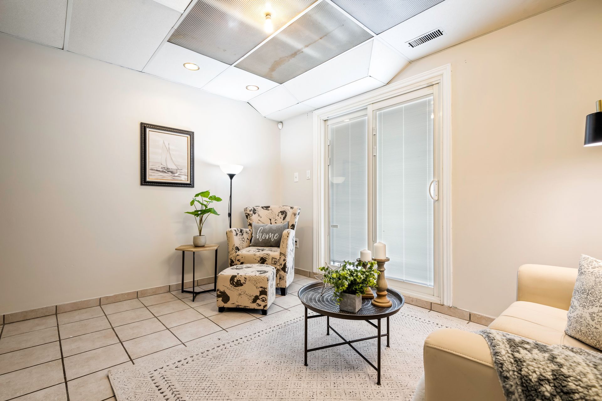 A living room with a couch , chair , coffee table and sliding glass doors.
