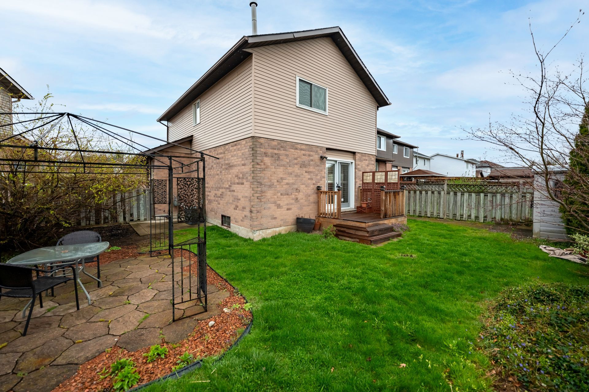 A house with a large lawn and a patio area in front of it.