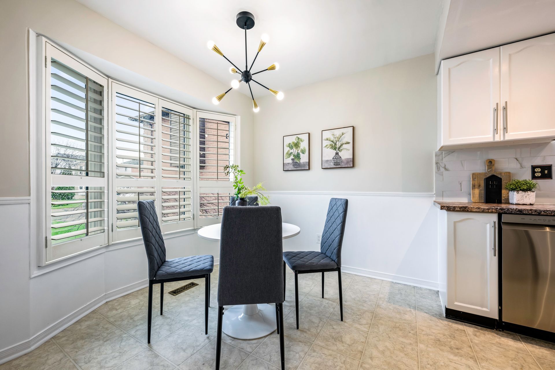 A dining room with a table and chairs and shutters on the windows.