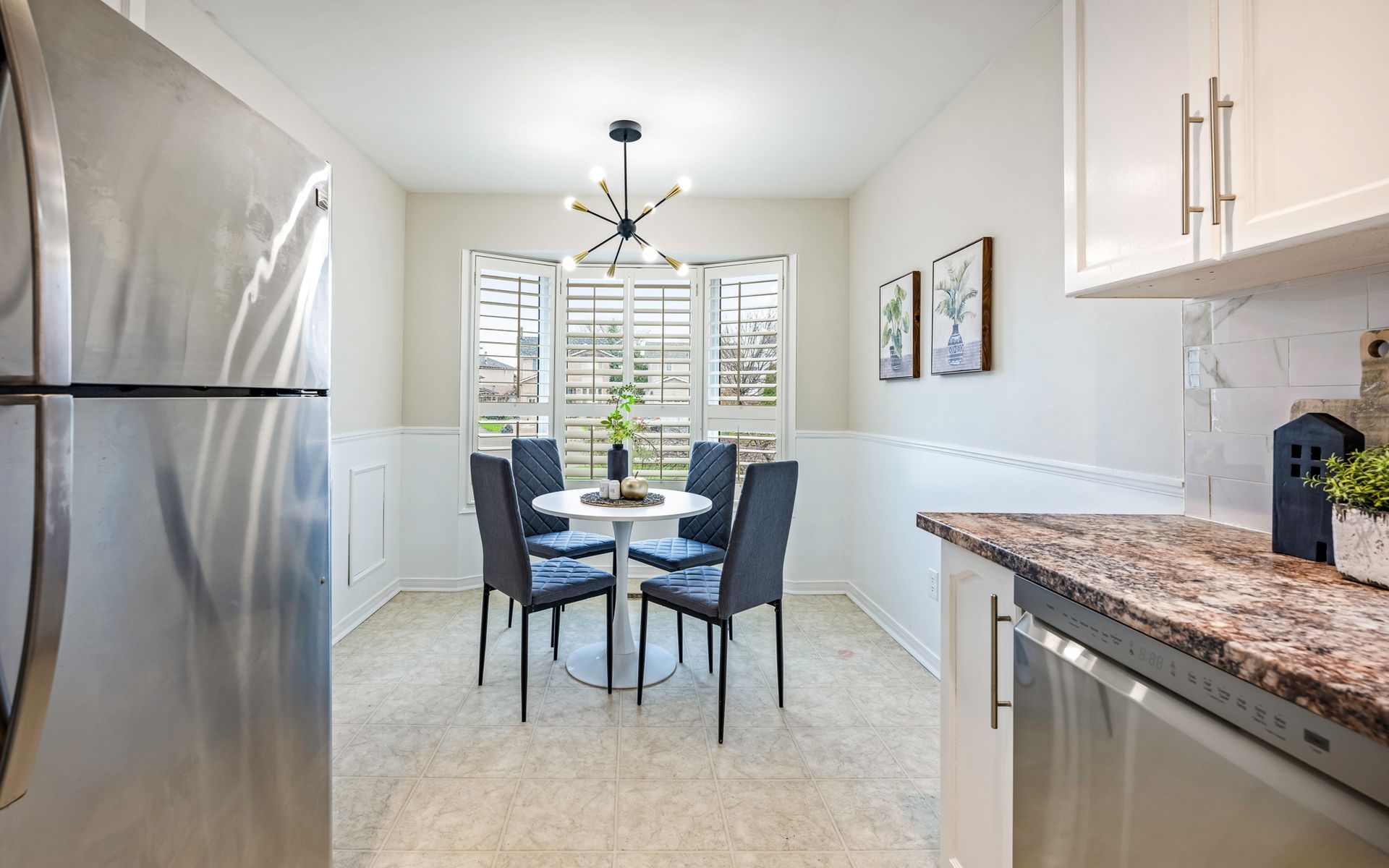A kitchen with a stainless steel refrigerator and a dining room with a table and chairs.