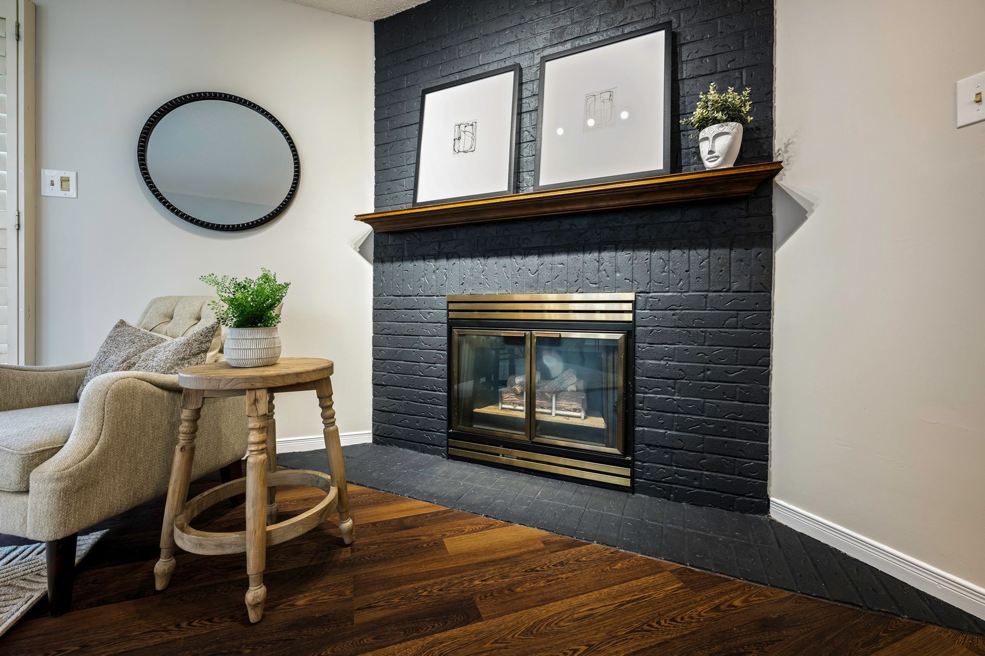 A living room with a fireplace , chair , table and mirror.