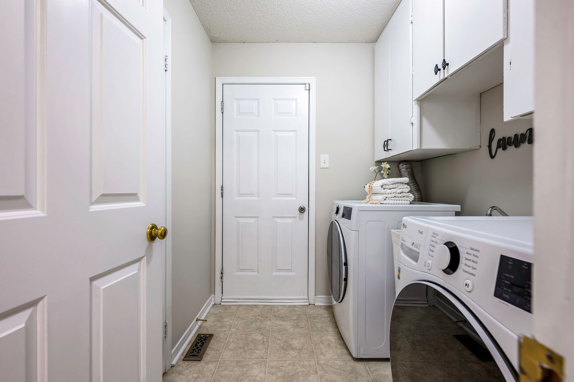 A laundry room with a washer and dryer and white cabinets.