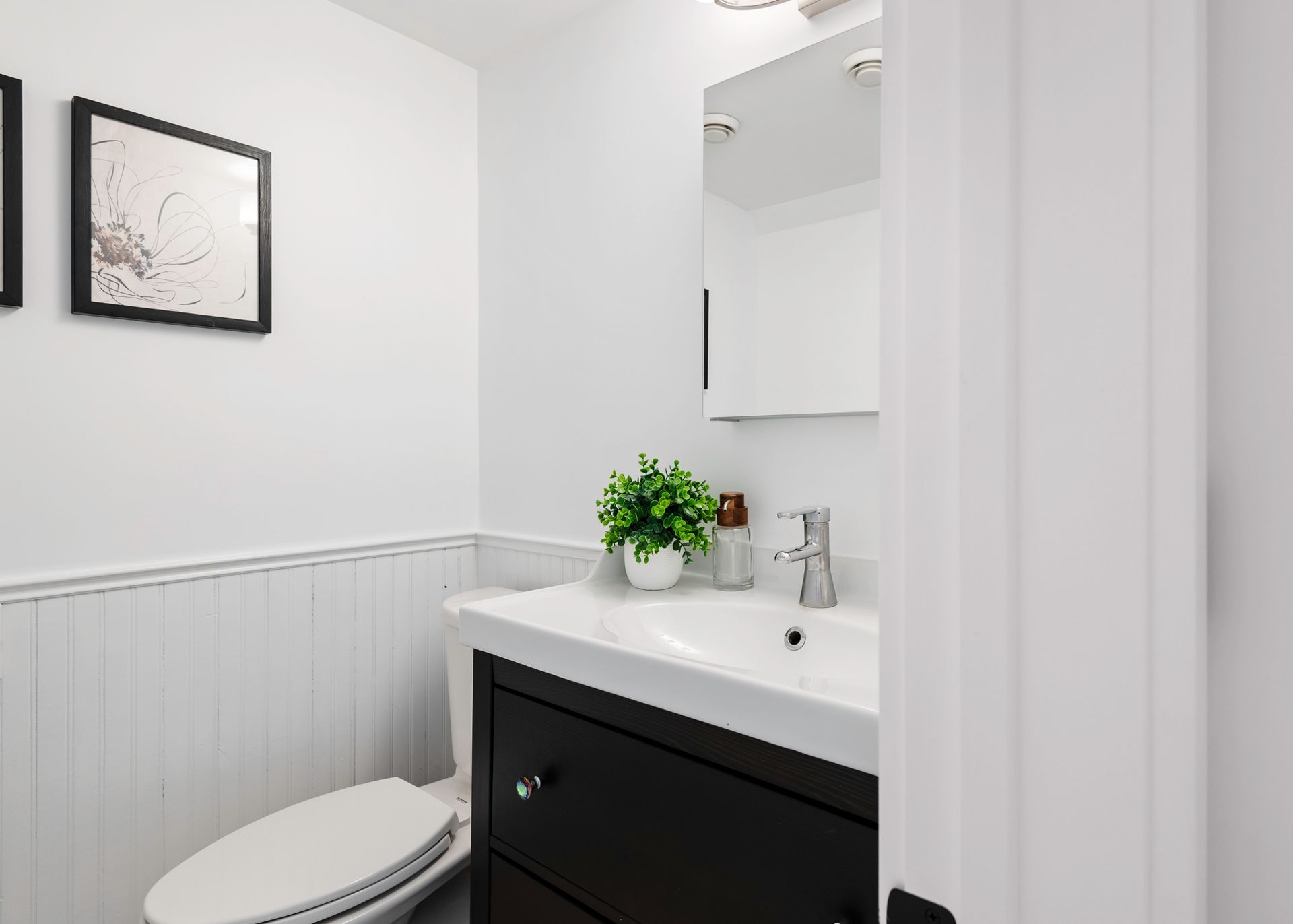 A bathroom with a toilet , sink and mirror.