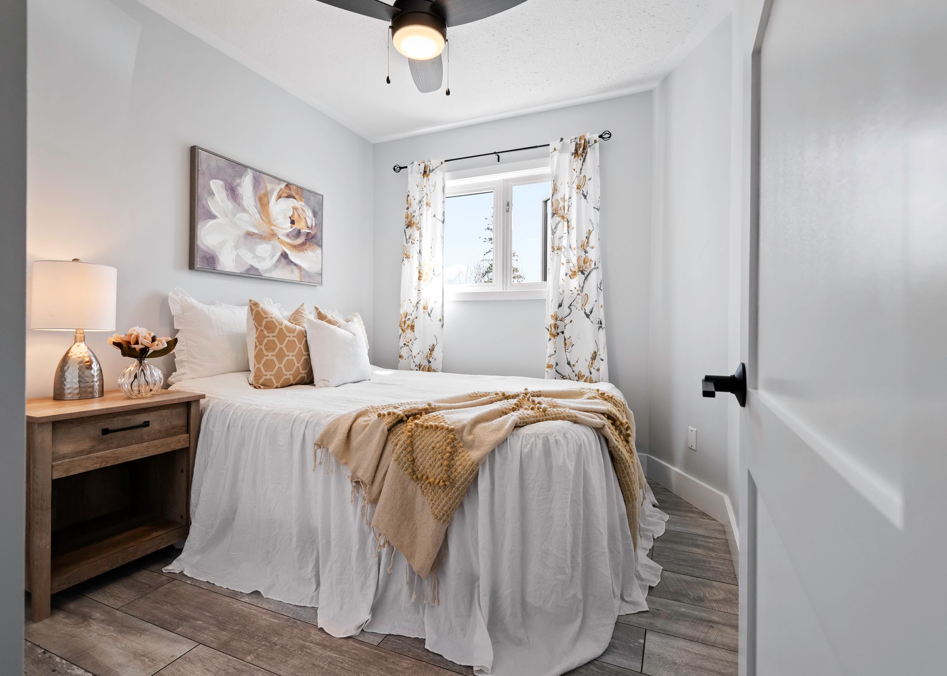 A bedroom with a bed , nightstand , lamps and a ceiling fan.