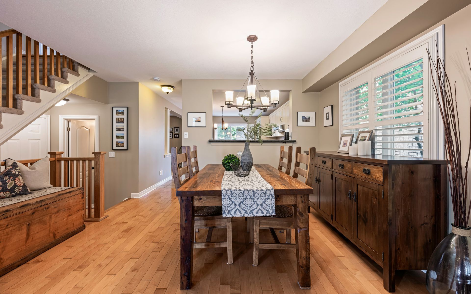 A dining room with a wooden table and chairs and a chandelier.